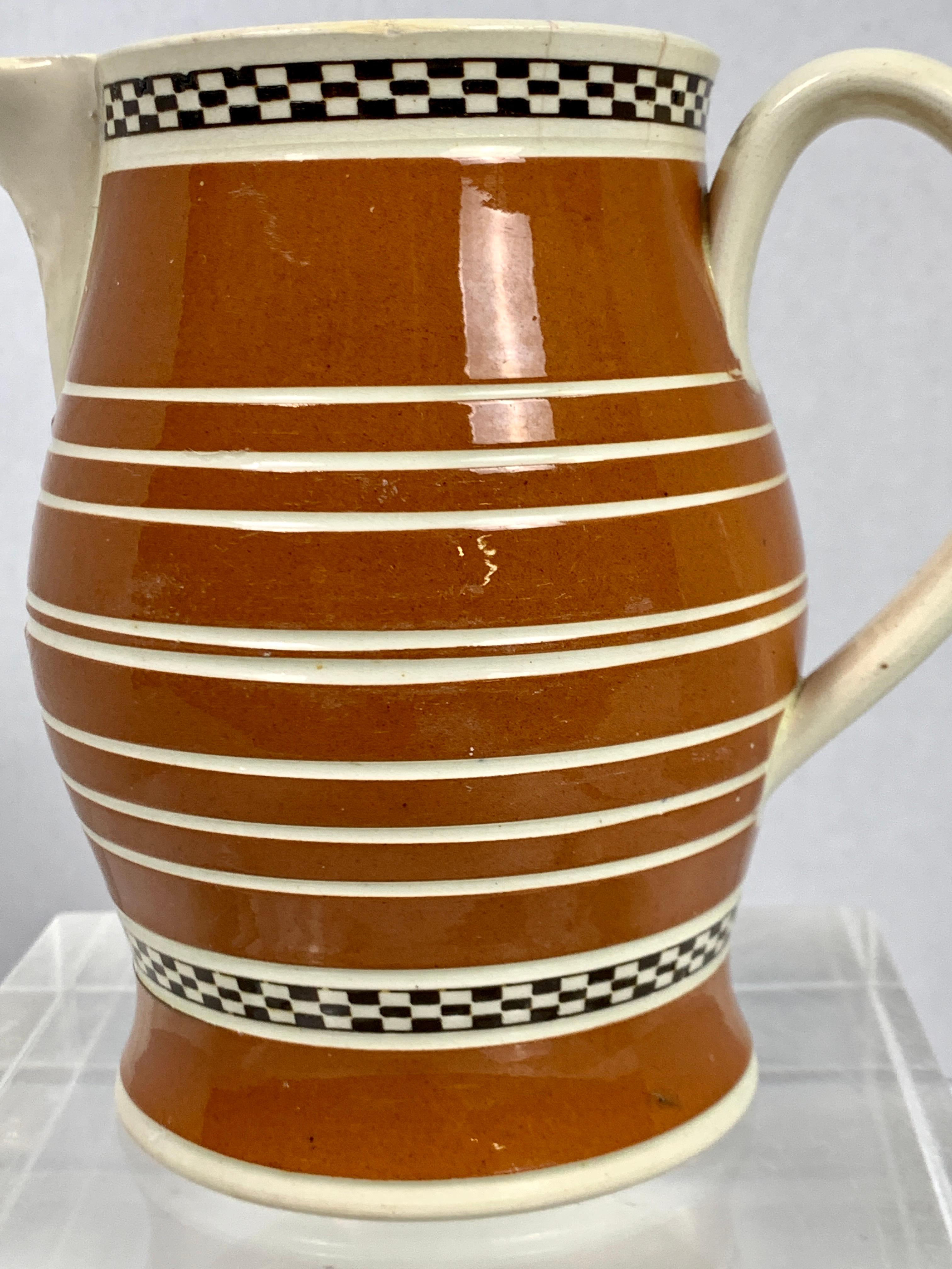 Made in England circa 1815 this mochaware pitcher is decorated with bands of lovely milk chocolate-colored slip. 
The color works beautifully with the unpainted creamware body of the handle and interior of the pitcher.
Just below the top edge, we