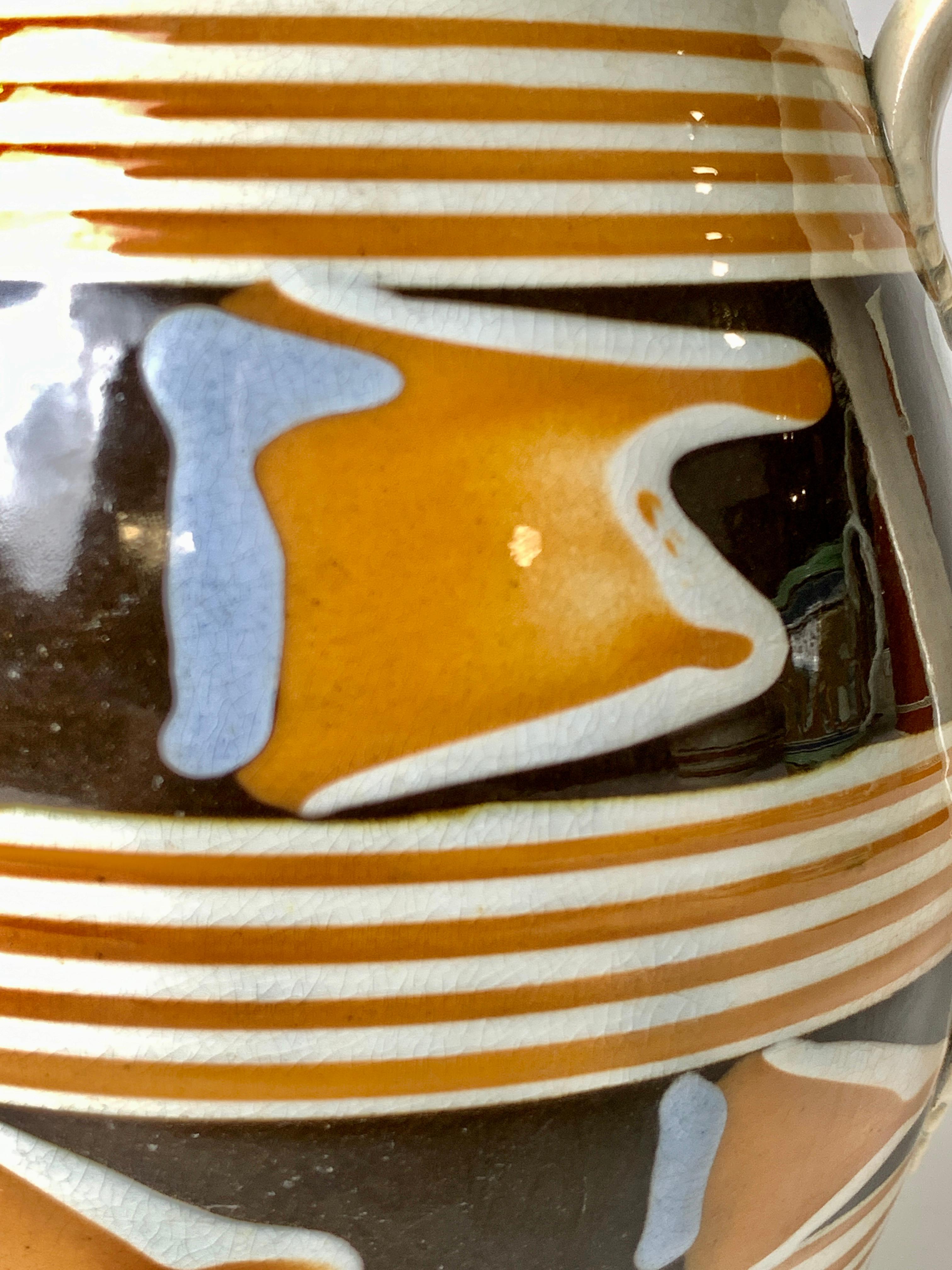 This mochaware pitcher was made of pearl glazed creamware in England circa 1820.
It has a unique design with freeform decoration in orange, light blue, and white on two wide black slip bands.
To make this design, the lathe operator would have