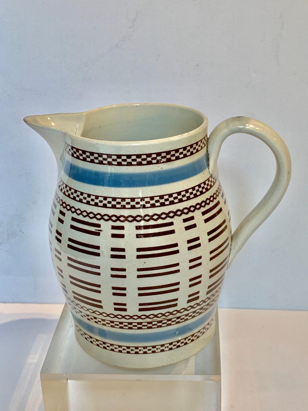 Mocha ware pitcher England, circa 1815. Decorated with baby blue bands of slip and bands of three geometric designs inlaid with black slip engine turning.
Dimensions: Diameter 3.75