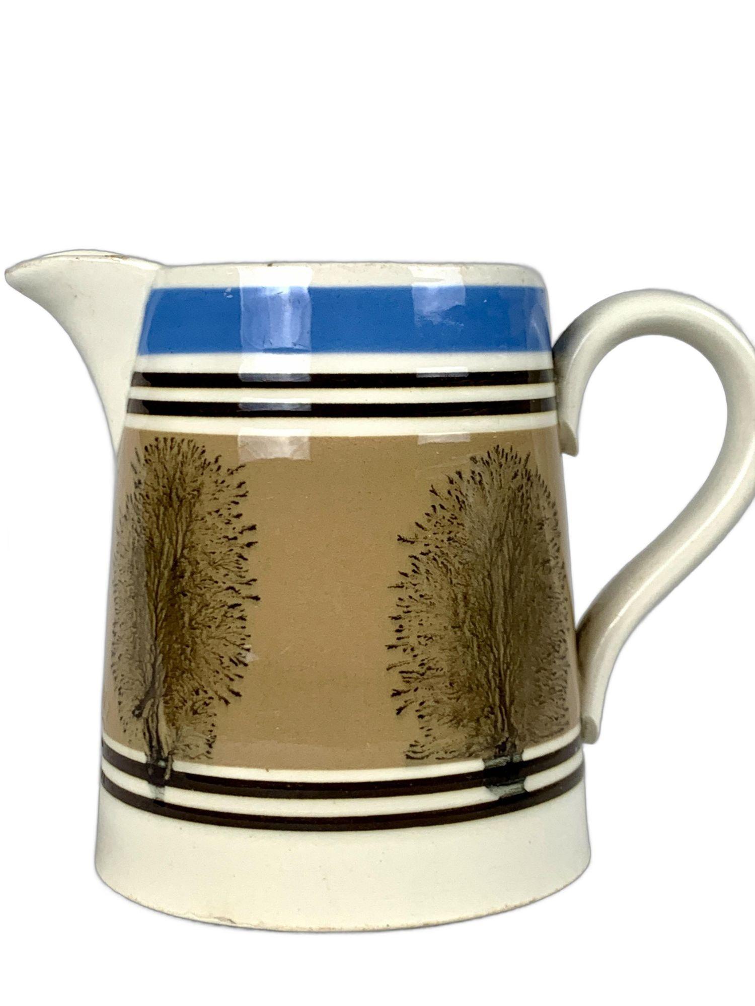 This mochaware pitcher was designed to hold a pint of beer or lager. It was crafted in England circa 1870.
The colors are soft, and the attractive design follows a pattern typical of English mochaware made for export to the European continent.