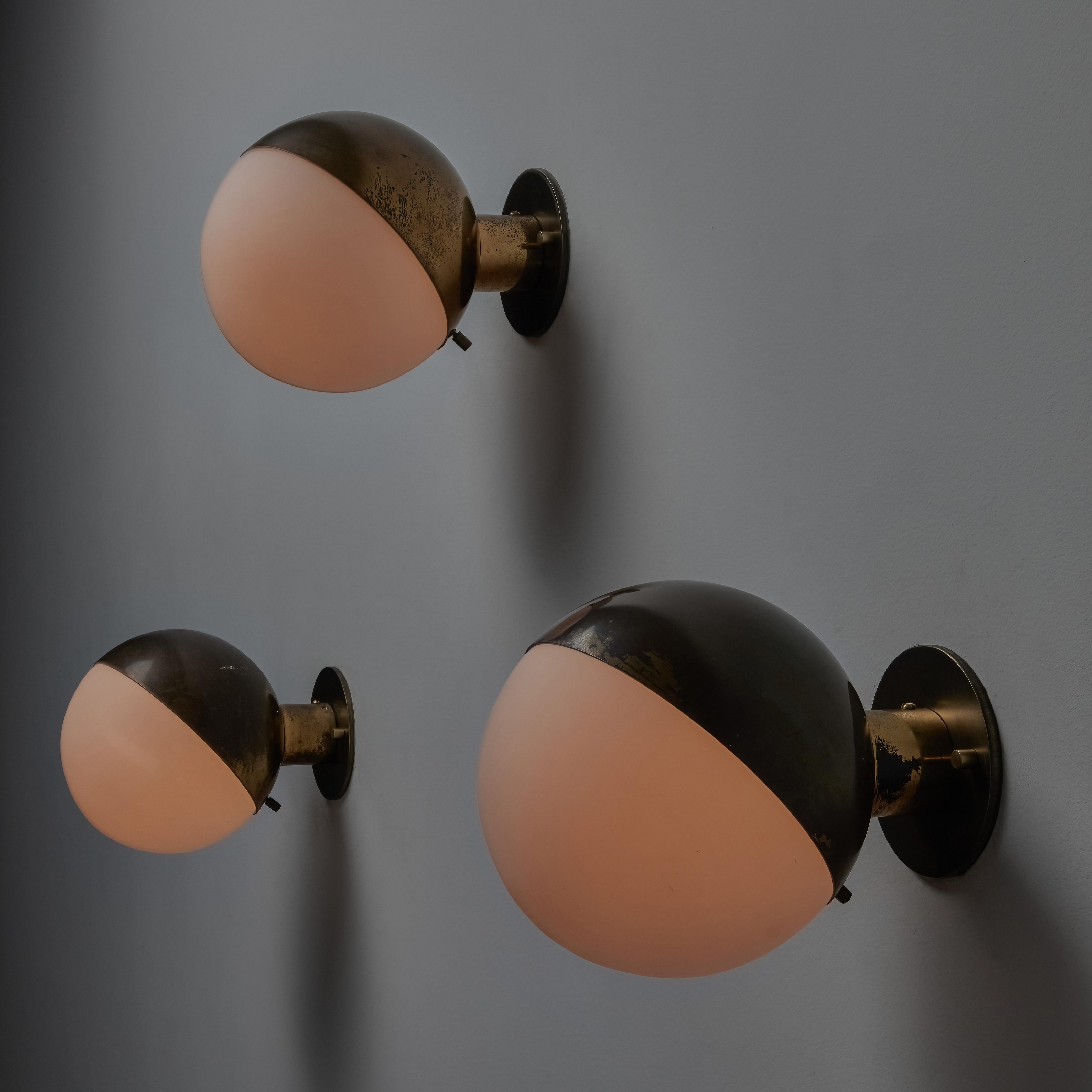 Model 2045 sconces by Stilnovo. Designed and manufactured in Italy, circa the 1950s. A true minimalist approach to these simple but striking ball sconces. A brass armature and top half shade, nestles a sandblasted opal glass globe. Each sconce
