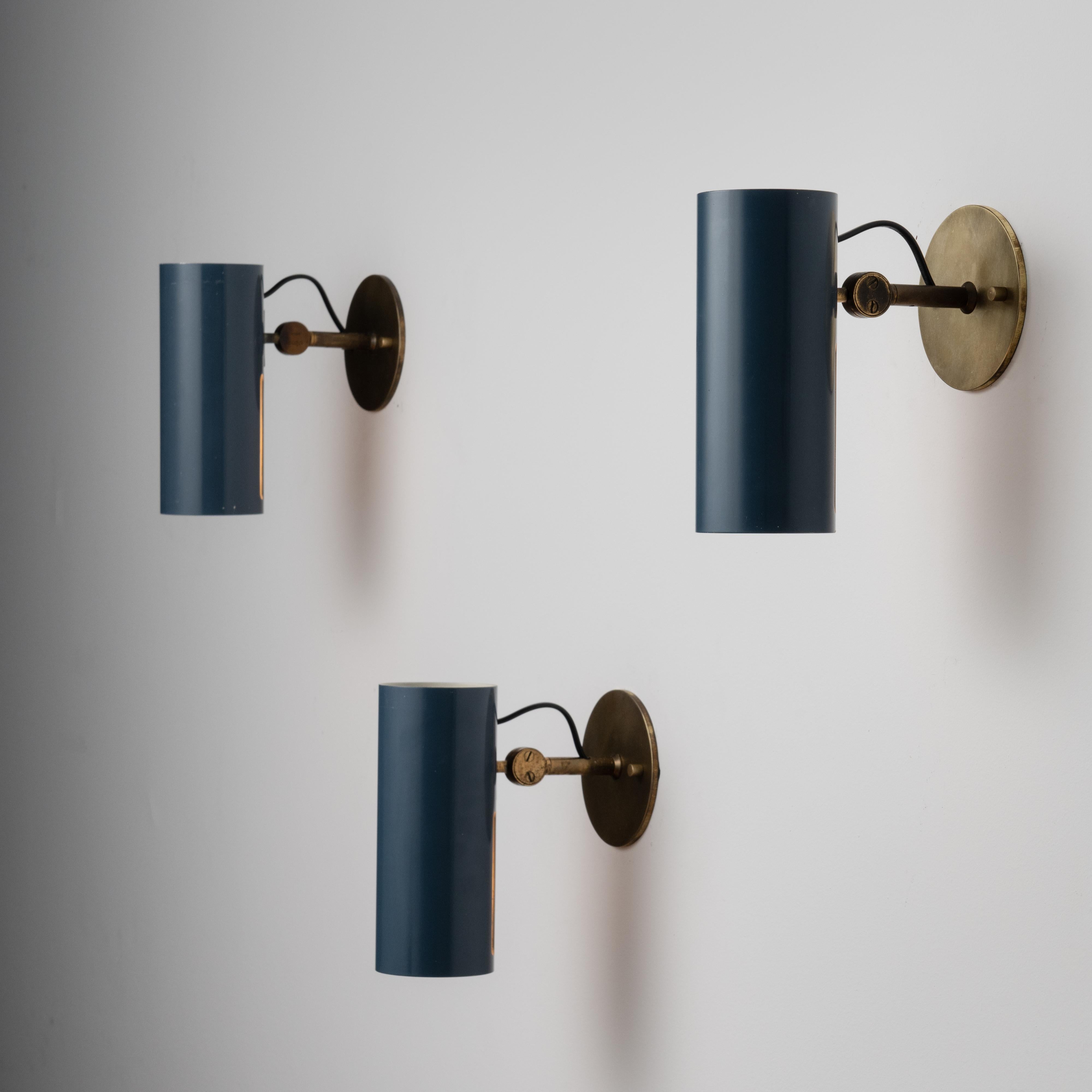 Mod. 2131 Sconces by Stilnovo. Designed and manufactured in Italy, circa the 1950s. Pivoting blue enameled cylinders work as utilitarian spotlights on these beautiful Stilnovo sconces. Brass armature and backplate represent the external components.