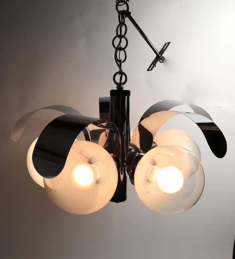 Chic and decorative mod midcentury chandelier having 5 art glass ball globe shades, each having an opaline white to clear fade surface, with a bright chrome body and dramatic curved arc elements. The fixture is in very fine, original, complete and