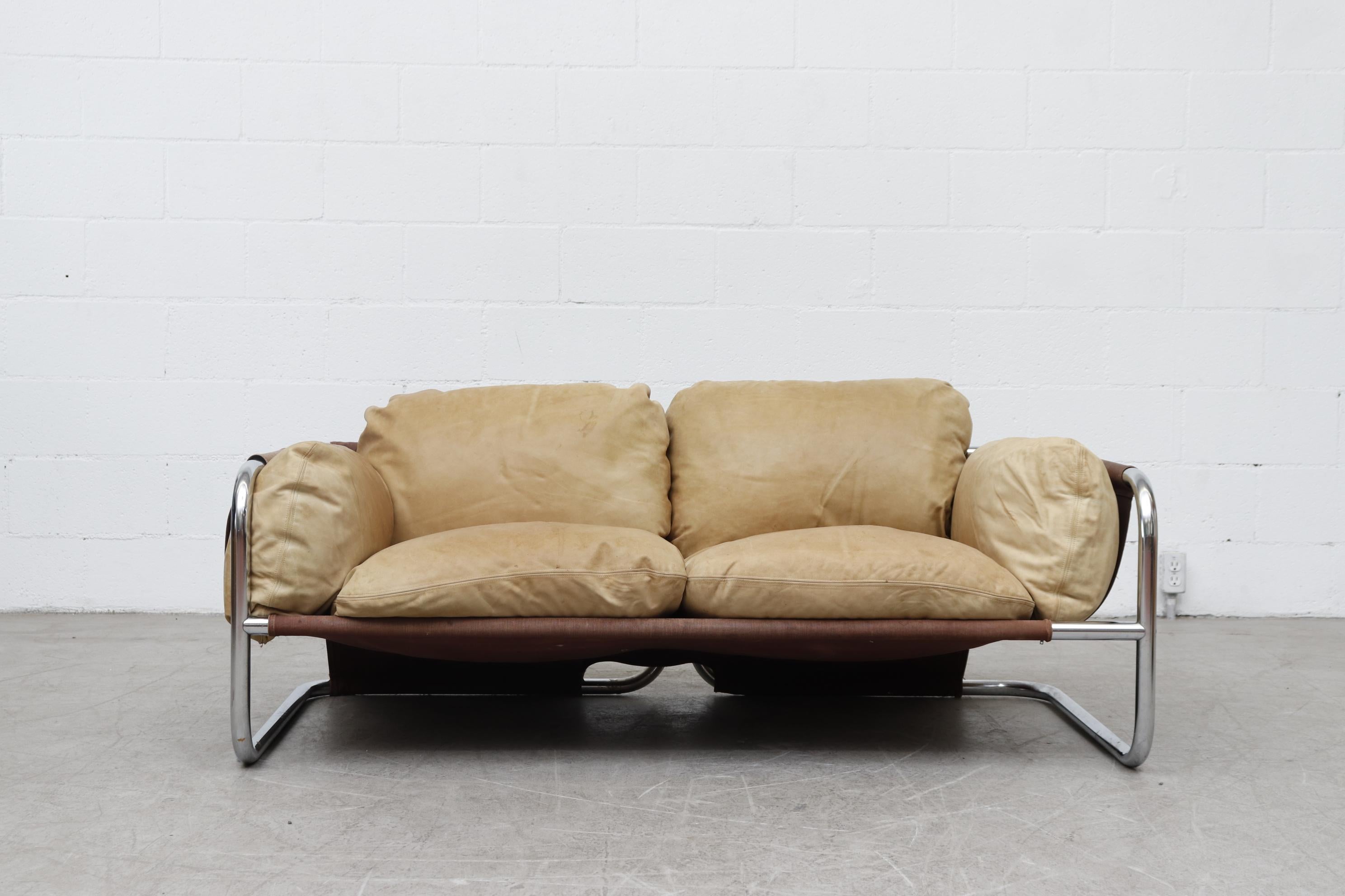 Incredible MOD Leolux midcentury well worn tan leather and chrome framed loveseat with canvas sling support. In original condition with visible patina and wear consistent with its age and use.