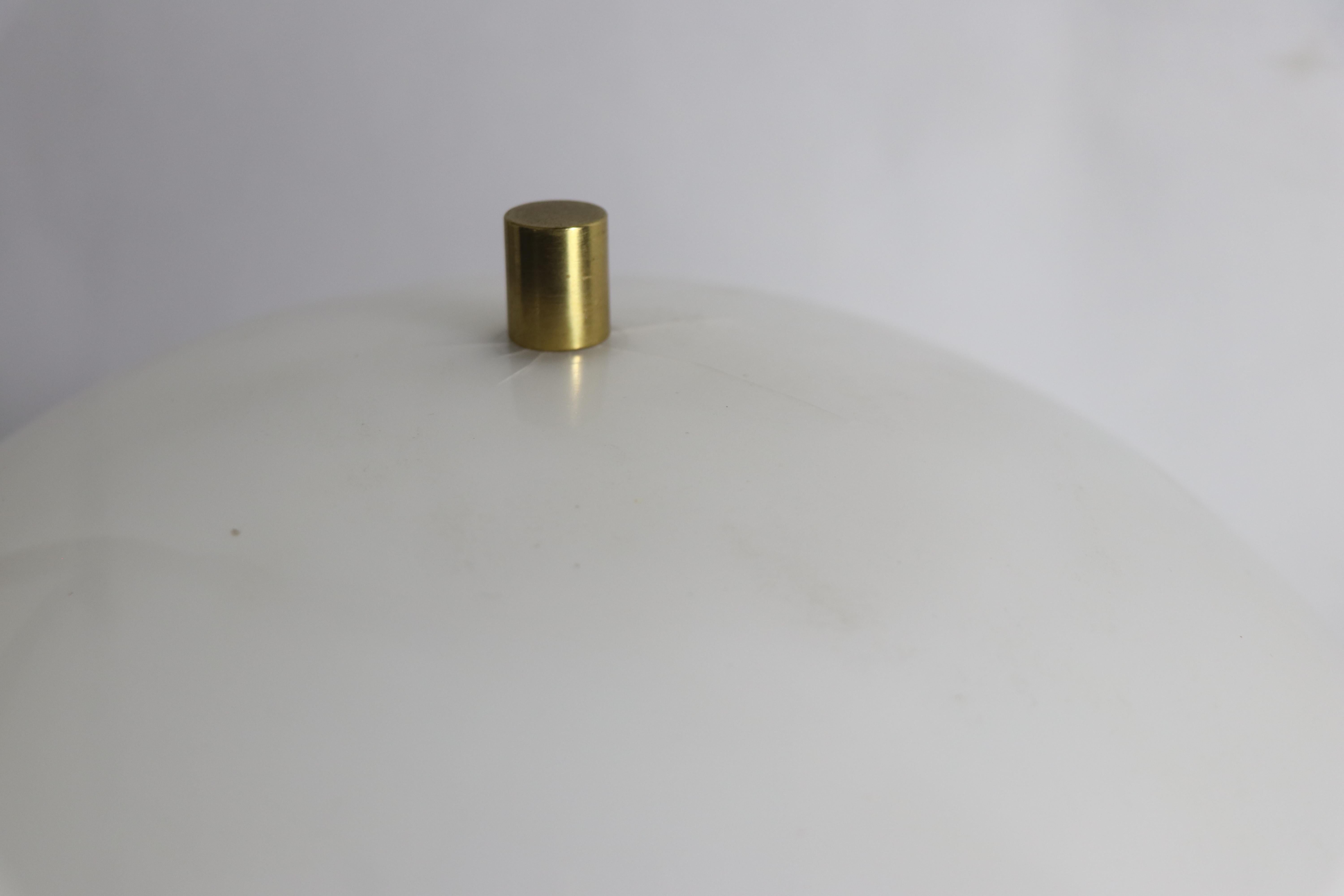 Architectural modernist table lamp attributed to Gerald Thurston for Lightolier. The brass base features a dramatic arc foot which is 7.5 W x 4.75 D inches, which supports a plastic dome shade 12 diameter, x 6 H inches - there plastic shade has some