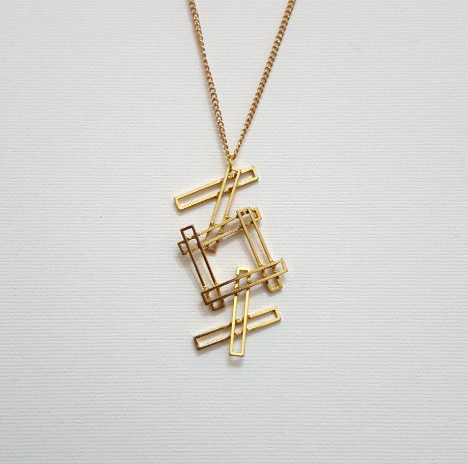 Collana con ciondolo geometrico in stile Mod/Mid-Century Modern, tonalità oro.
Ci piace questo lungo ciondolo, molto MCM, un po' nello stile di Jere o forse del brutalismo.  
Il retro presenta due graffi nel metallo (come si vede nell'ultima
