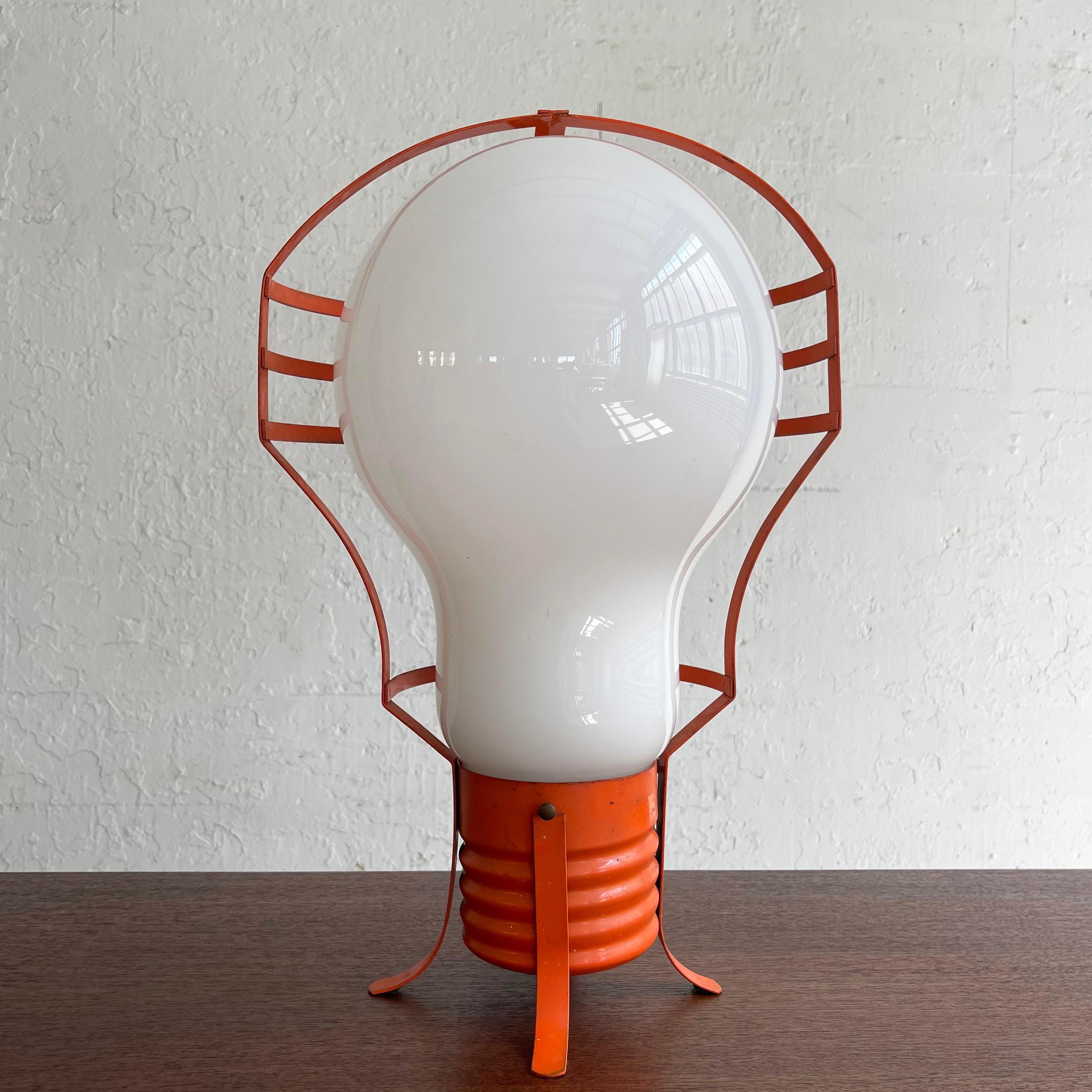 Mod, italienisch, Mid-Century Modern, Pop Art, Tischlampe mit einem übergroßen Milchglas-Glühbirnenschirm in einem orange lackierten Metallrahmen. Die Lampe kann aufrecht auf dem Sockel stehen oder auf der Seite liegen.