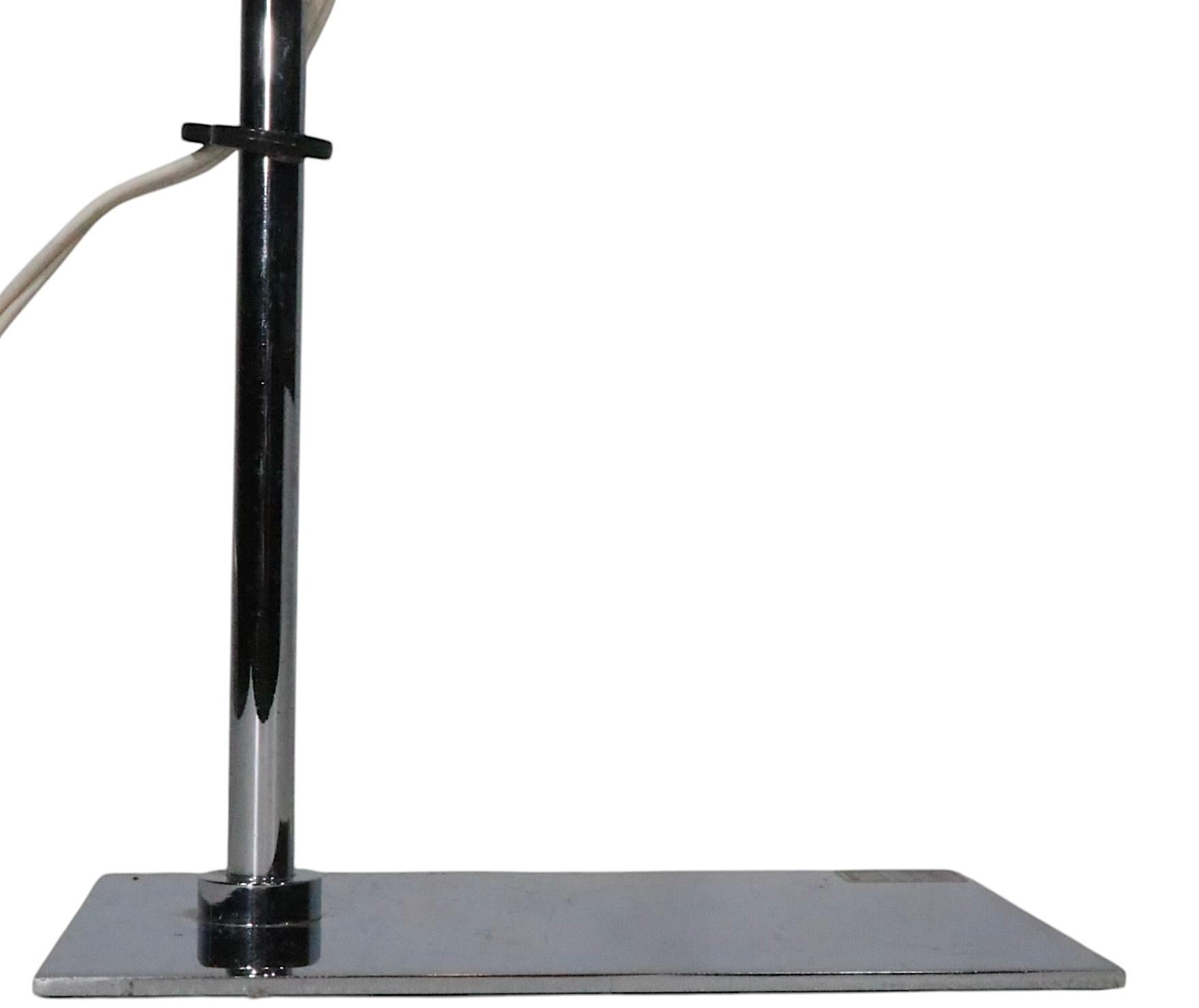 Exceptional Modernist, Space Age, Mid Century adjustable desk lamp by Robert Sonneman, circa 1970's. This model, known as a TIK lamp,  features a perforated metal disk form shade in white enamel paint finish, with a chrome vertical standard, on a