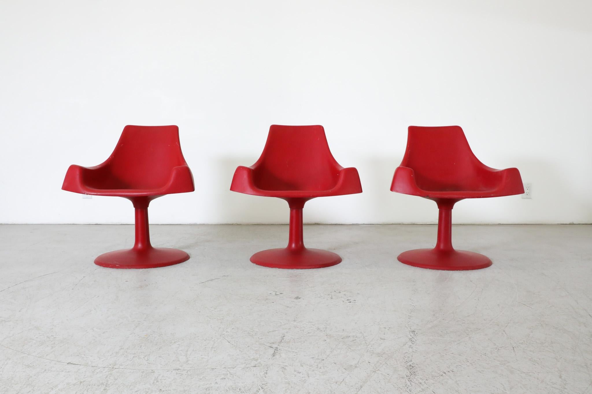 Space age mod Eero Saarinen inspired red plastic molded armchairs with fixed pedestal base. In original condition with visible wear consistent with its age and use. three available.