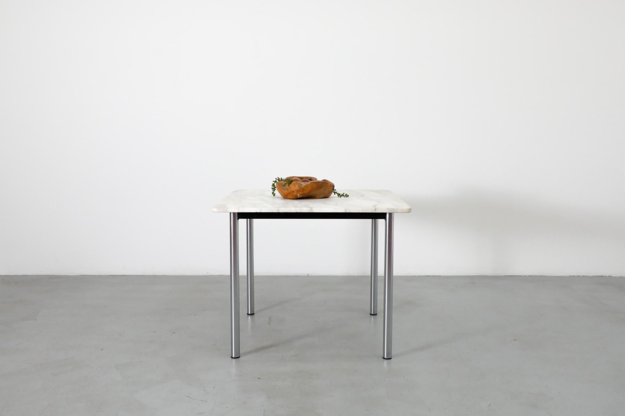 Table de salle à manger du milieu du siècle dernier avec plateau carré en marbre et pieds tubulaires chromés. Le dessus a été renforcé par des blocs de bois fixés au cadre. Bon état général avec une usure visible correspondant à son âge et à son