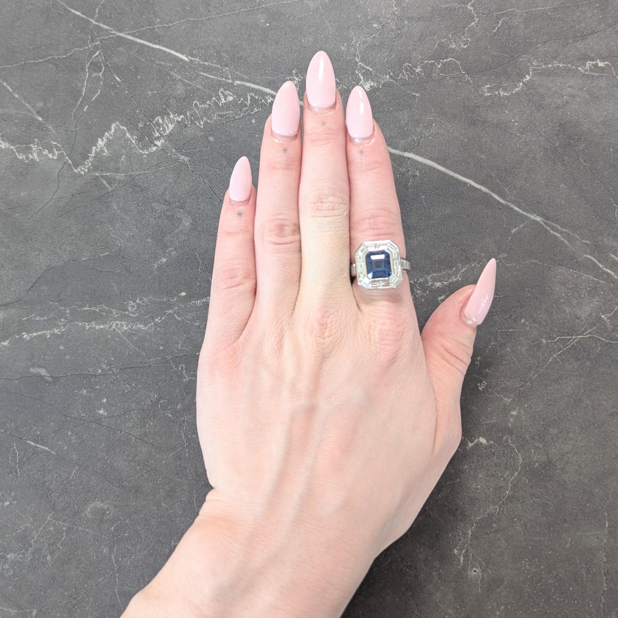 Centering an emerald cut spinel weighing 5.54 carats - transparent medium violetish blue
Natural and displaying no indications of heat treatment - bezel set with halo surround
With additional diamonds channel set in shoulders - all tapered baguette