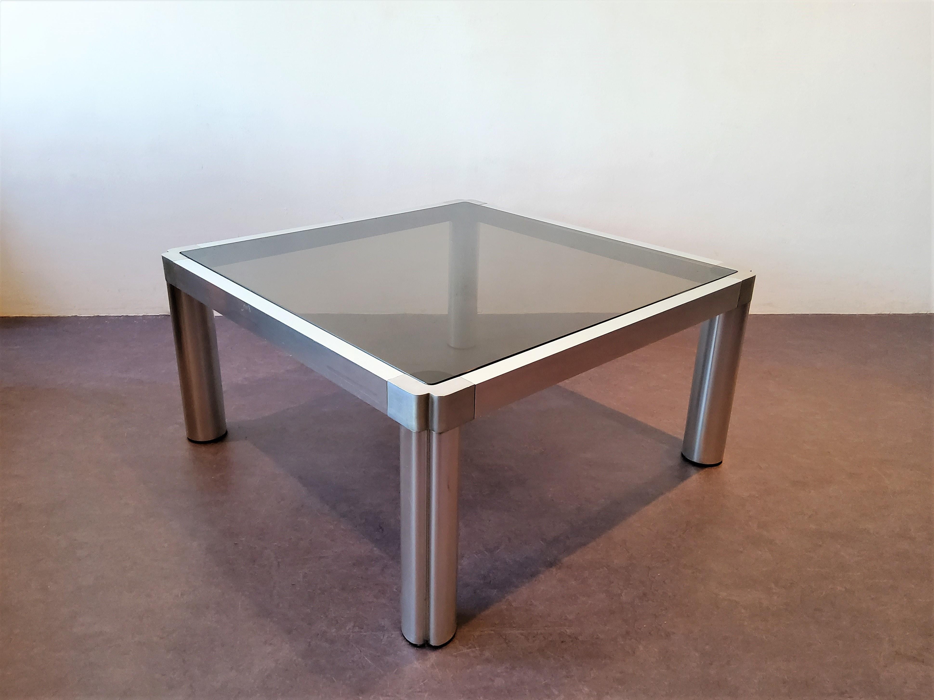 This coffee table, model 100, was designed by Kho Liang Ie for Artifort in 1974. It has an extruded and andonized aluminum base with a smoked glass top. This table is in a very good condition, with minor signs of age and use and some small scratches