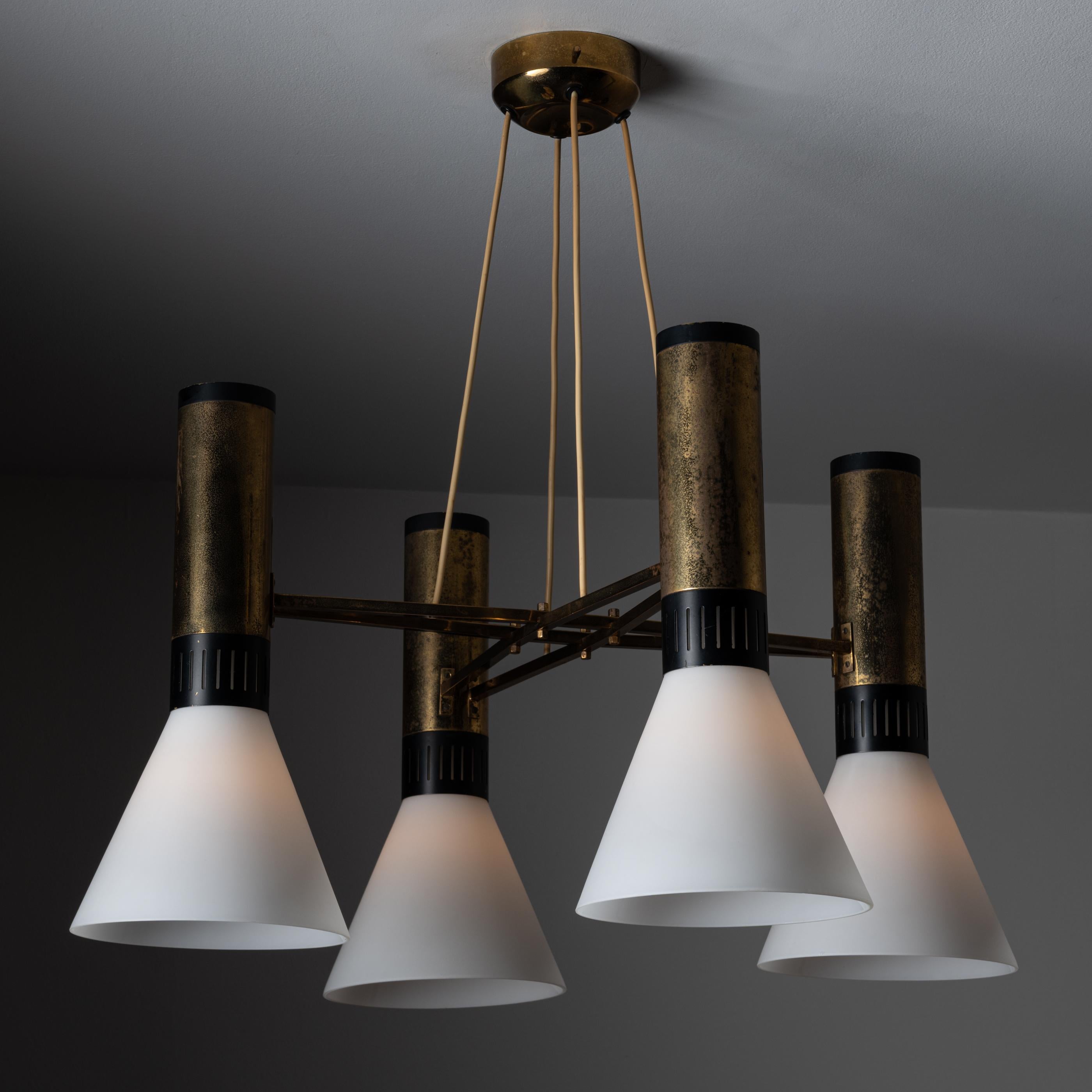 Model 1174 chandelier by Stilnovo. Designed and manufactured in Italy circa 1960. Chandelier is composed of a brass frame featuring black lacquered details surrounding the neck of four frosted cone shaped glass fixtures. We recommend four E27 60w