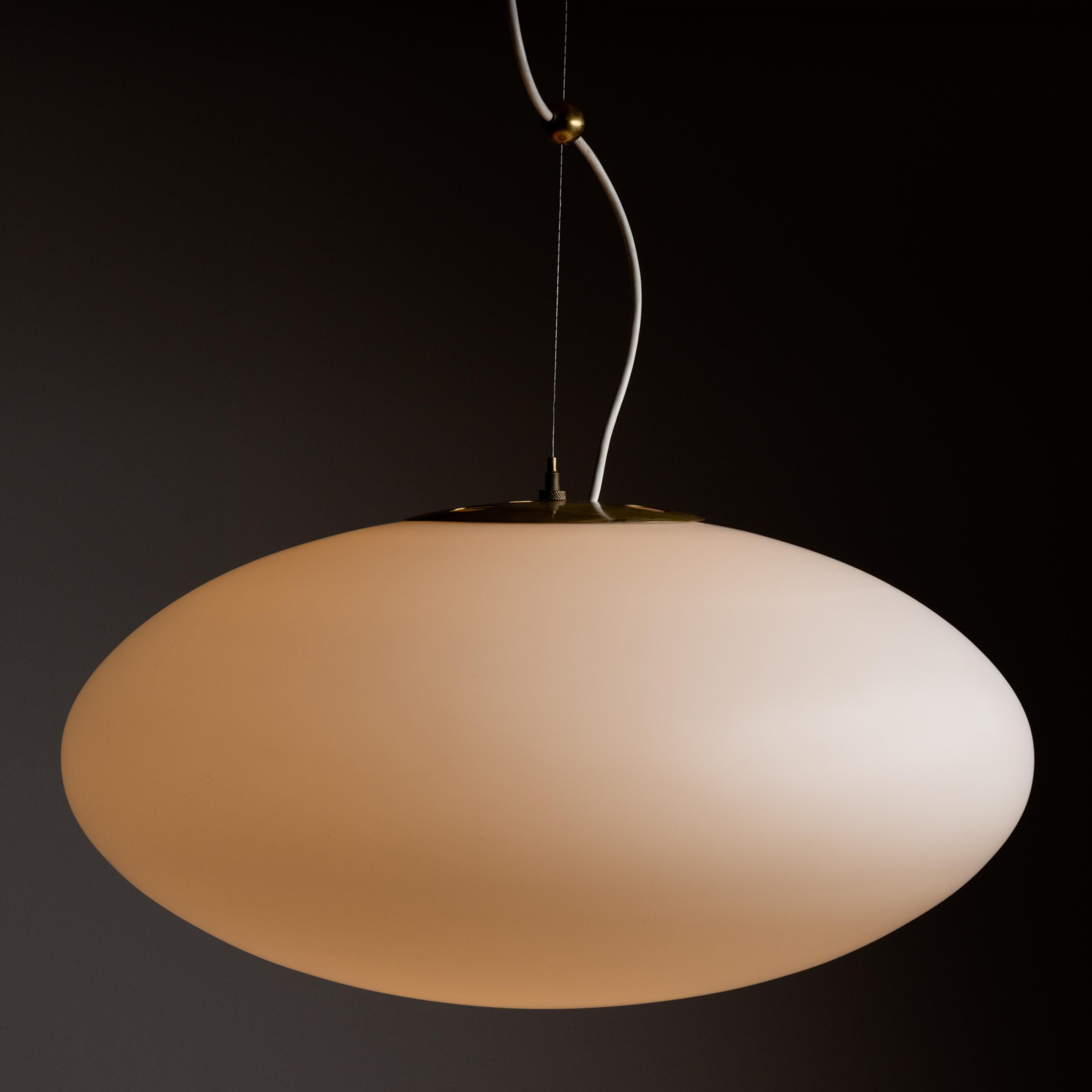 Model 1187 ceiling lamp by Gaetano Sciolari for Stilnovo. Designed and manufactured in Italy, 1953. Ceiling mounted by a cylindrical brass canopy, wire length is slightly adjustable with wire pulley detail. Opal glass lantern provides soft and