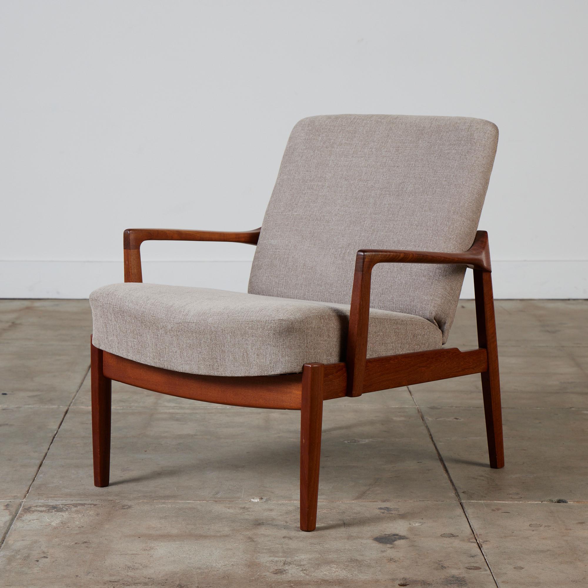 A low, Danish lounge chair by husband and wife design team Tove and Edvard Kindt-Larsen for France & Son. This example from 1958 has a teak frame around fixed cushions, upholstered in a soft taupe textile. The design is distinguished by its bowed