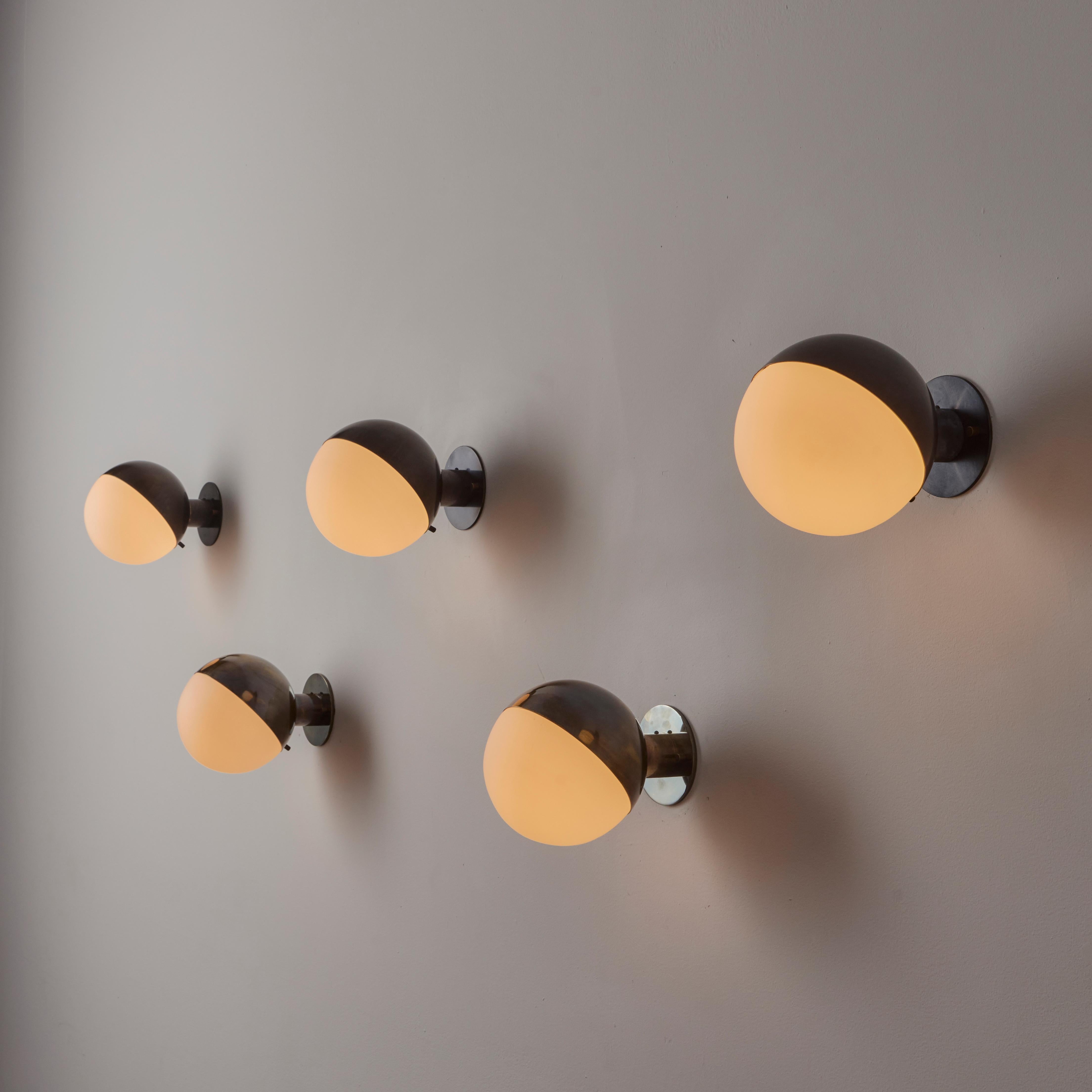 Appliques modèle 2045 de Stilnovo. Conçu et fabriqué en Italie, vers les années 1950. Une véritable approche minimaliste pour ces appliques boule simples mais saisissantes. Une armature en laiton et un demi abat-jour supérieur abritent un globe en