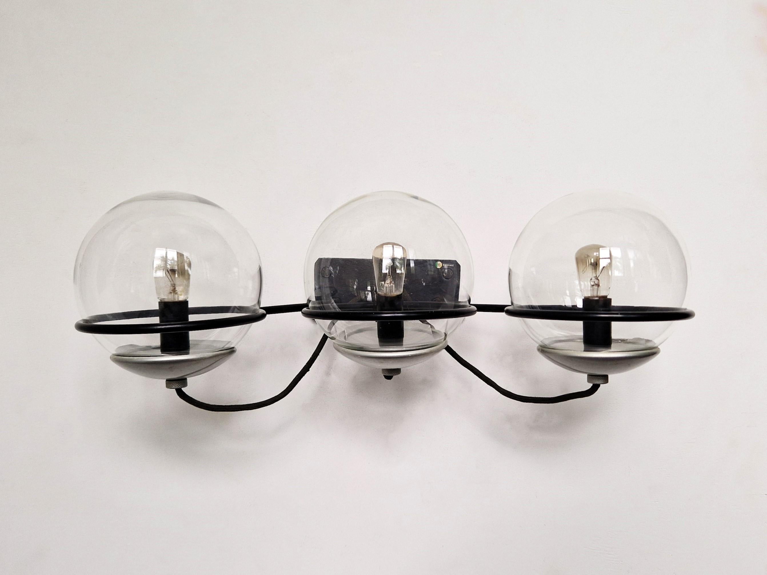 This amazing wall sconce was designed by Gino Sarfatti for Arteluce in the 1950's. It has an elegant black lacquered metal frame that holds 3 transparent glass globes. With the right bulbs a warm and gentle light can be spread. The diameter of each