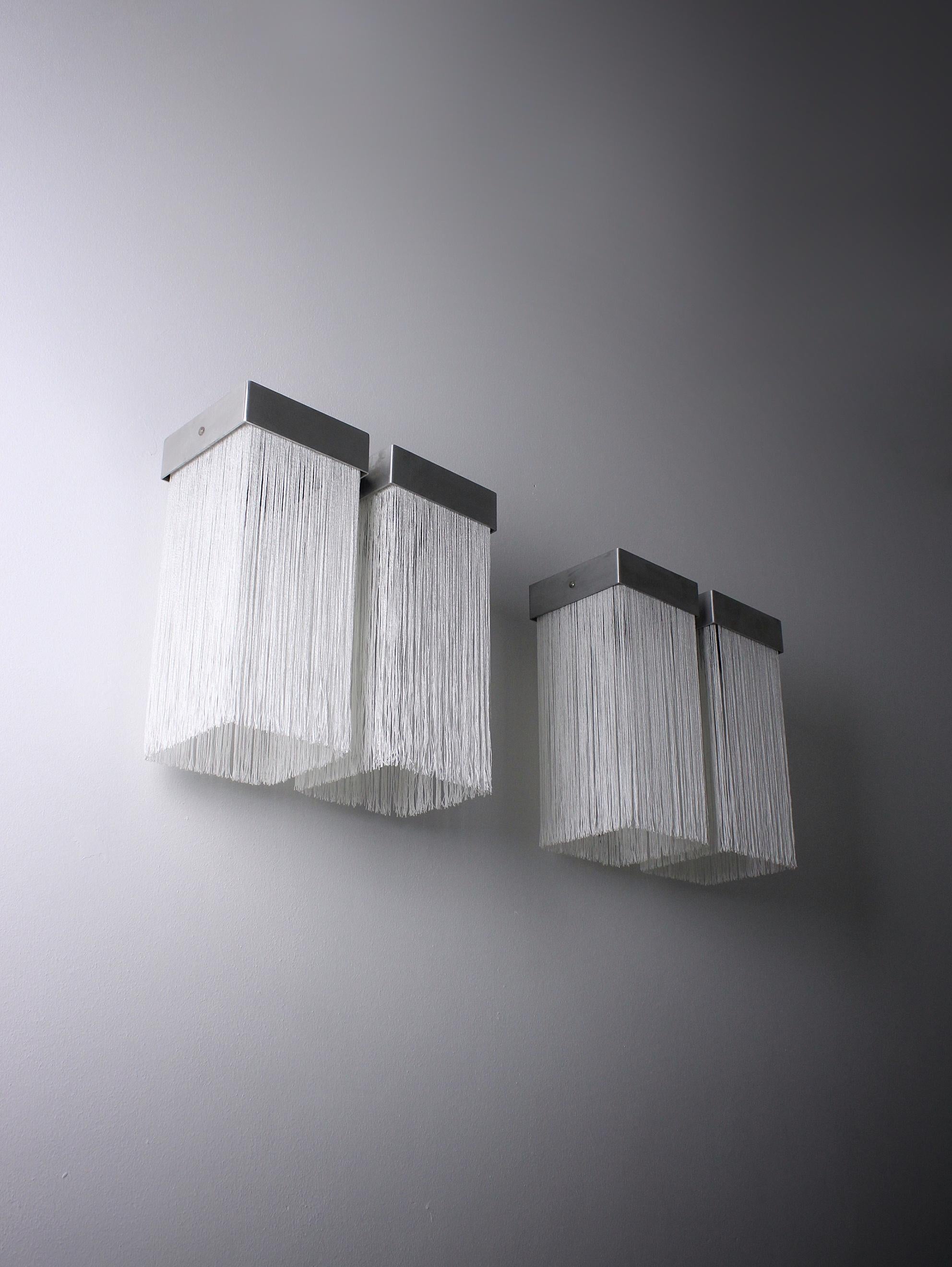 The Model 259/2 wall lights, a highly uncommon design by Massimo Vignelli dating back to 1964, stand out for their construction using anodized aluminum frames and fabric fringes surrounding the light source. This model boasts multiple variations,
