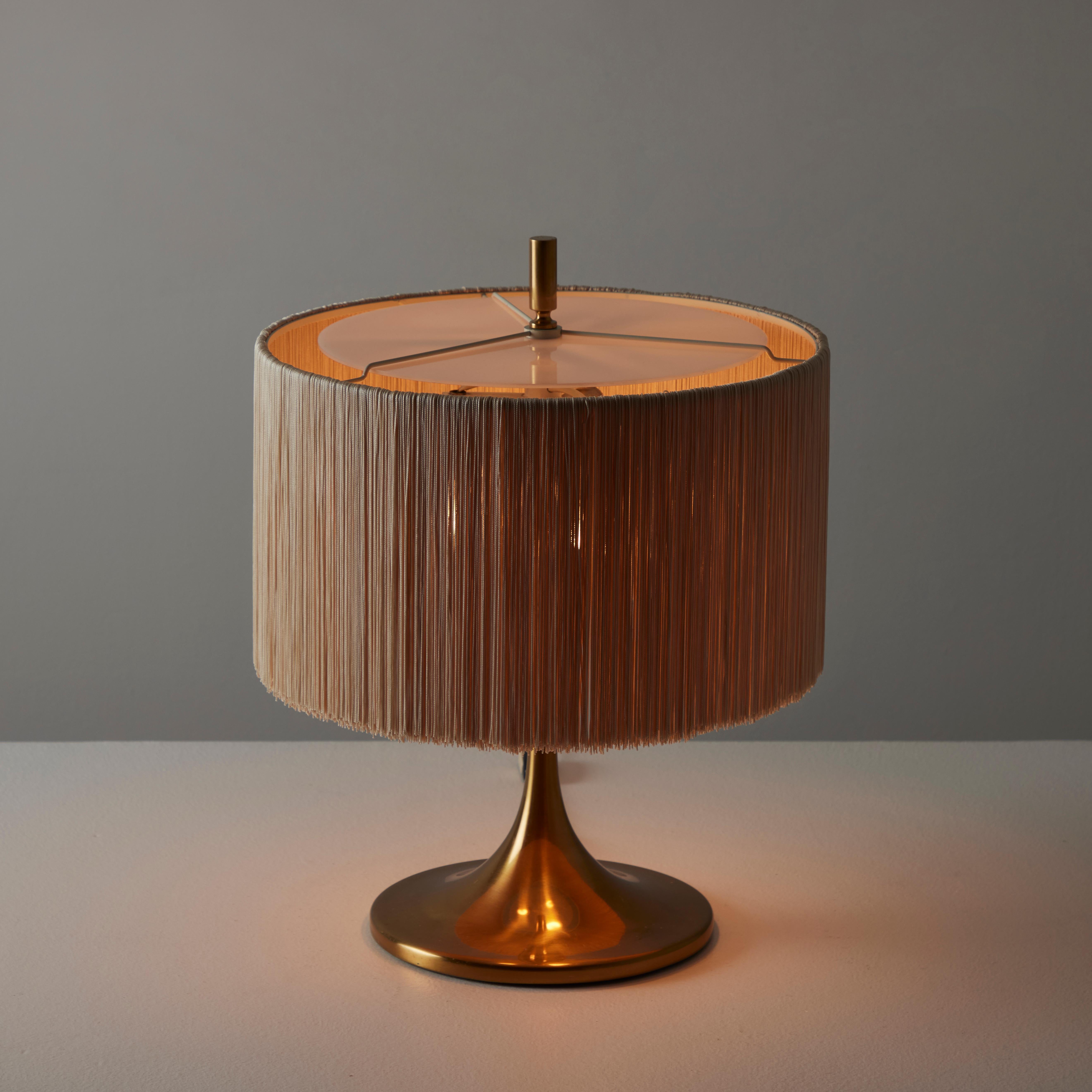 Model 282 Table Lamp by Paolo Caliari for Oluce. Designed and manufactured in Italy, circa the 1960s. Tulip polished brass base, paired with a fringe shade. The shade is a cream colored fringe cylinder with an acrylic op diffuser. The light holds a