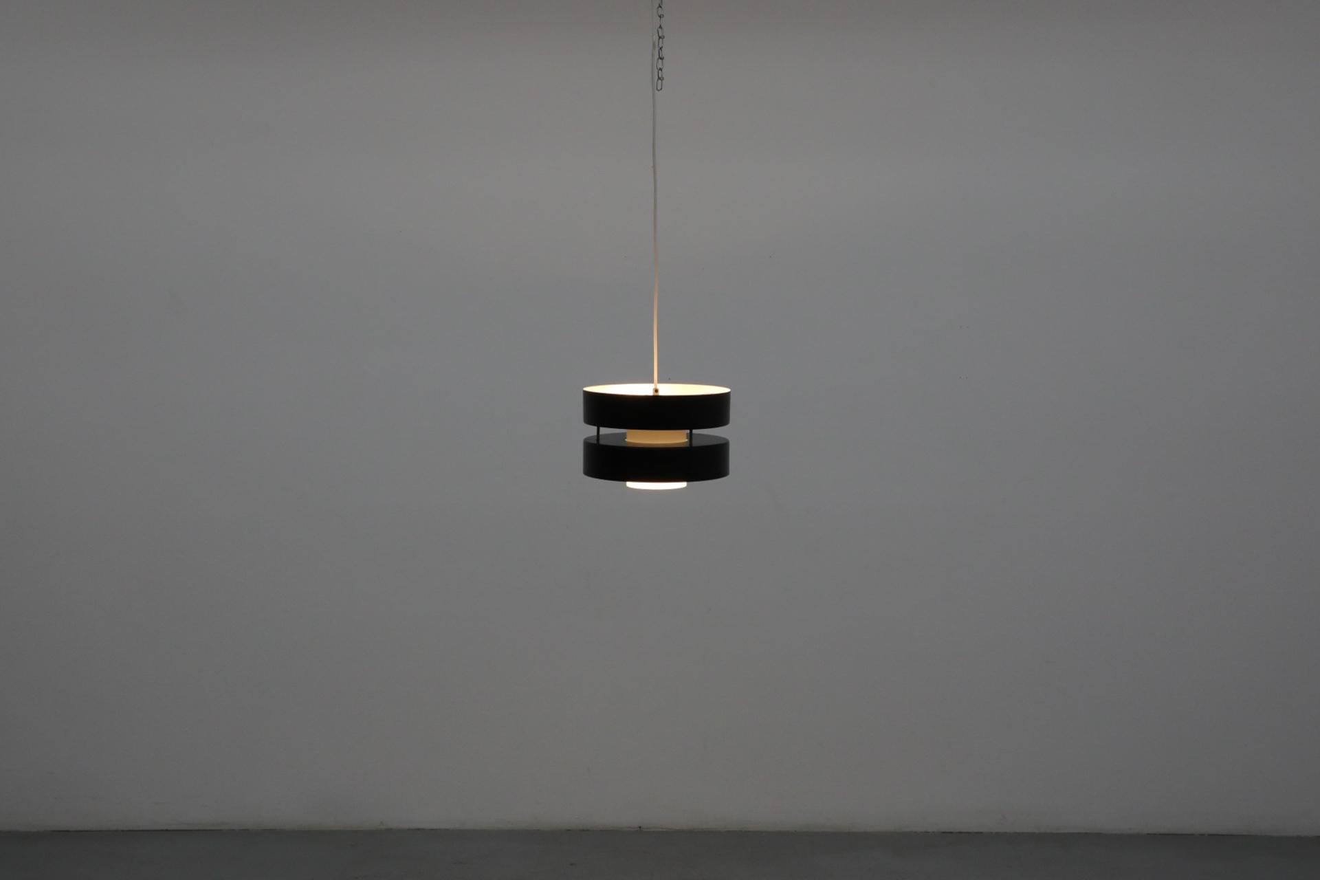 Lámpara colgante de doble barra Hagoort con exterior esmaltado en negro, interior blanco hueso y pantalla interior de cristal de leche. Moderno diseño de dos niveles con tomas de candelabro europeo en la parte superior y una toma de base mediana