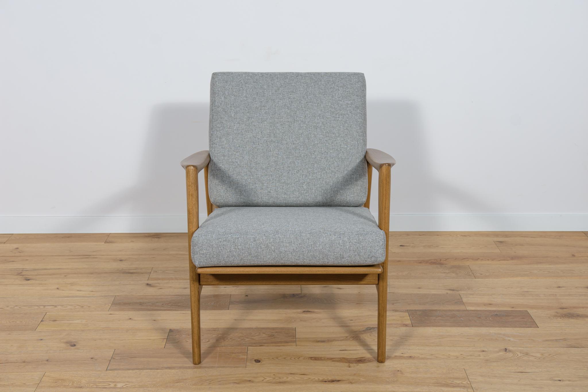 The armchair was produced by the Polish company Swarzędzka Furniture Factory in 60 s. The armchair have new cushions,  reupholstered in a quality dark grey fabric. The beech frame has been cleaned from the old surface, painted with a walnut colored