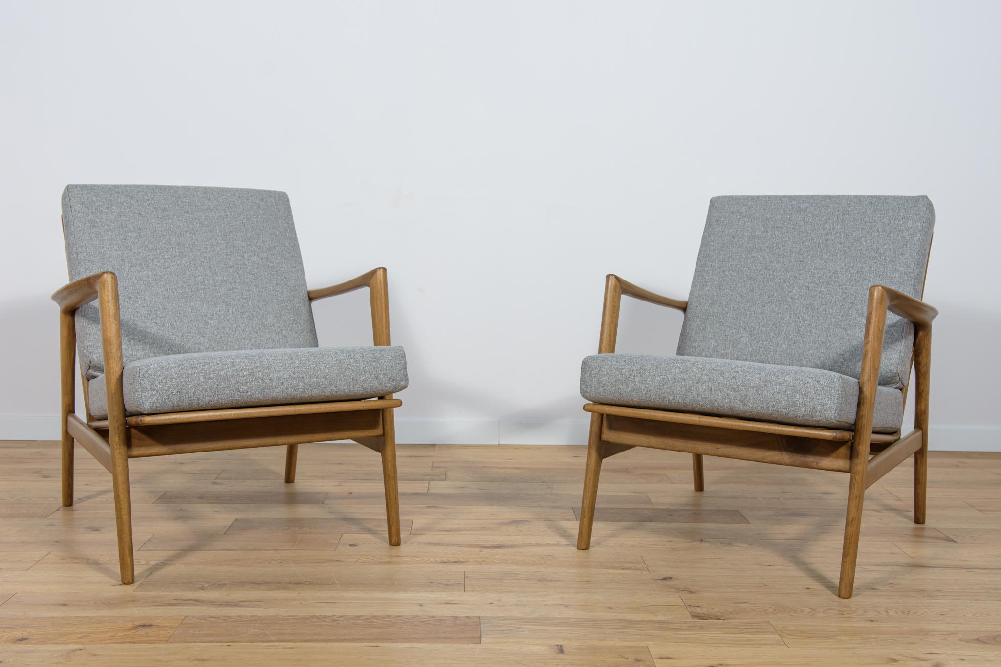 This pair of armchairs was produced by the Polish company Swarzędzka Furniture Factory in 60s.The armchairs have new cushions, reupholstered in a quality dark grey fabric. The beech framehas been cleaned, painted with a walnut colored stain, and
