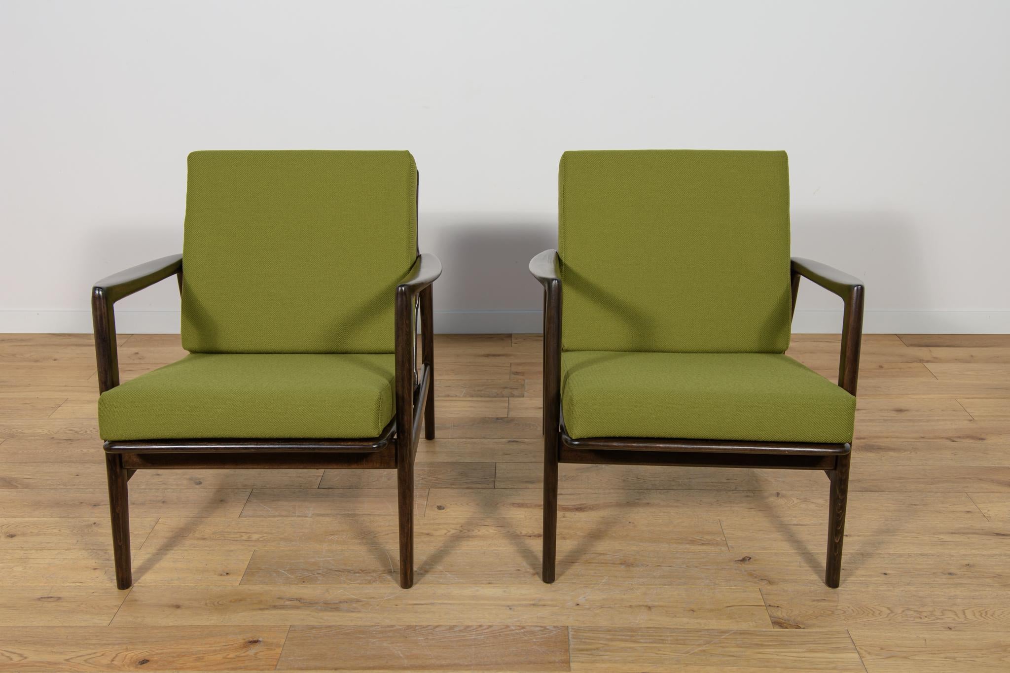 This pair of armchairs was produced by the Polish company Swarzędzka Furniture Factory in 60s.The armchairs have new cushions, reupholstered in a quality green fabric. The beech framehas been cleaned from the old surface, painted with a rosewood