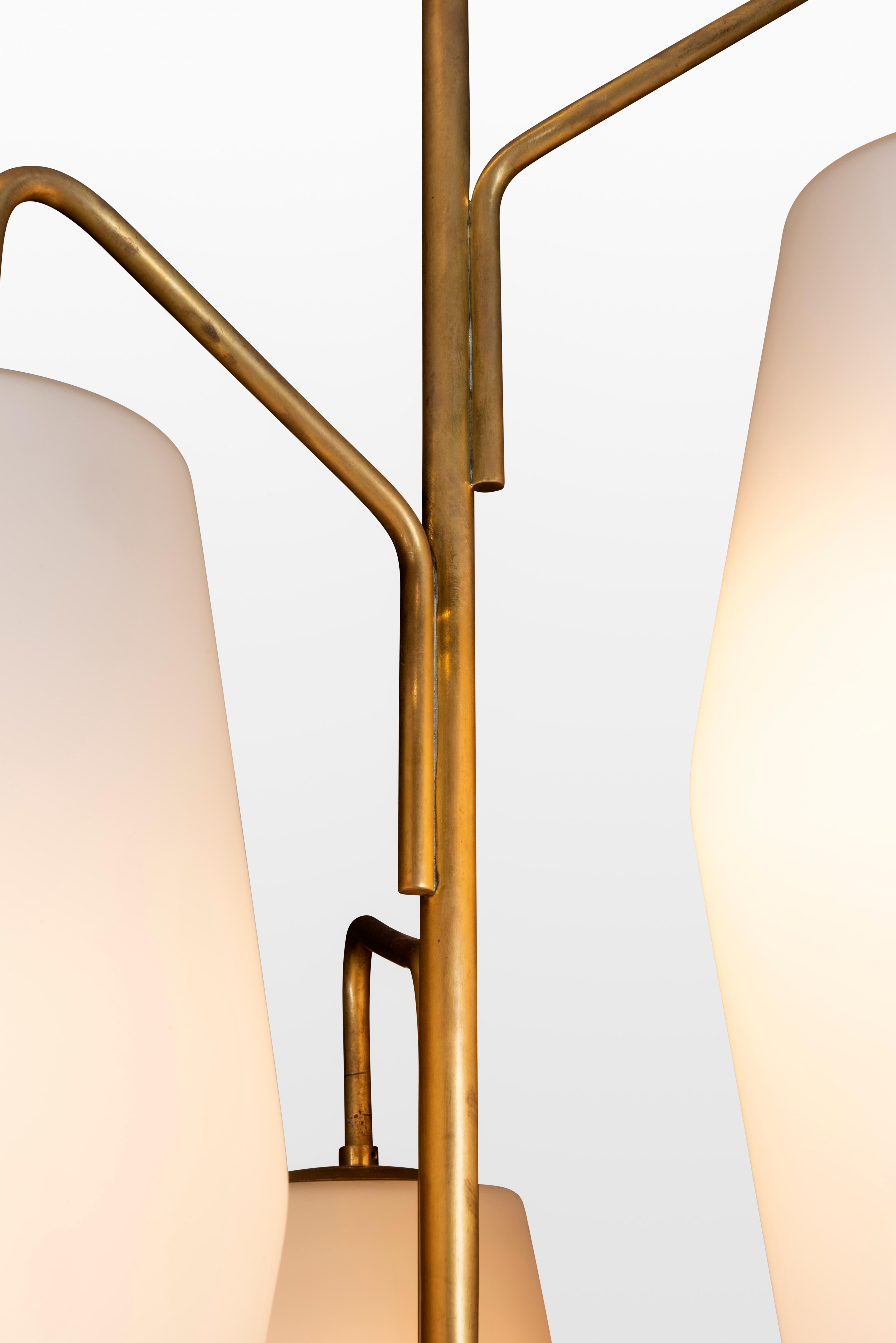 Stilnovo floor lamp model 4052 has three opaline glass lantern shades suspended on gilt lacquer arms and black enameled stem ending on a Carrara marble base, Italy, 1960s.