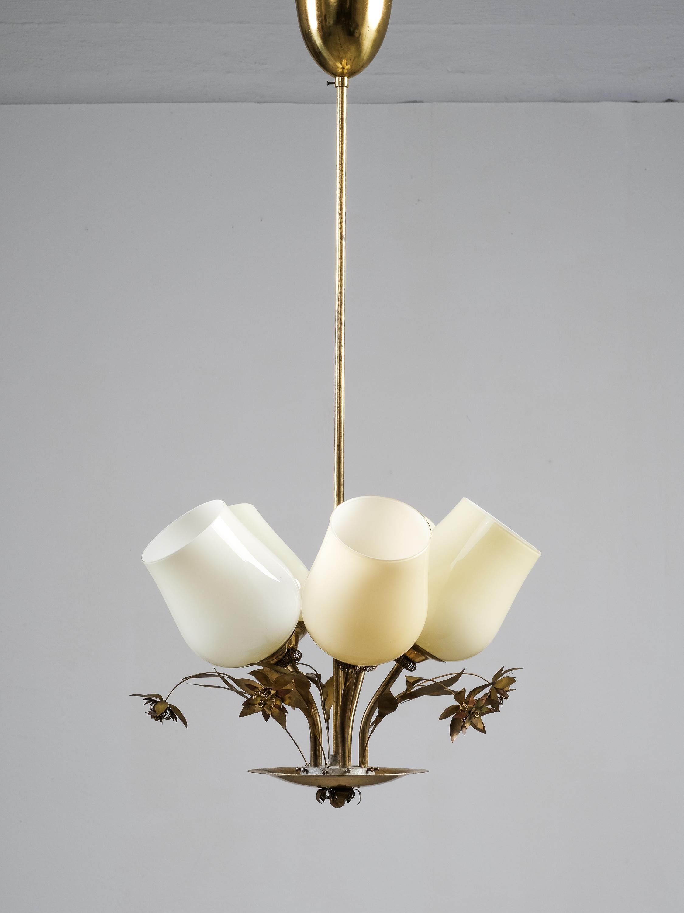 Magnifique et délicat lustre en laiton finlandais du milieu du siècle par Stockmann. La lampe est composée de cinq bases lumineuses avec des abat-jours en verre opalin et de belles décorations florales en laiton entre chaque base. Il présente des