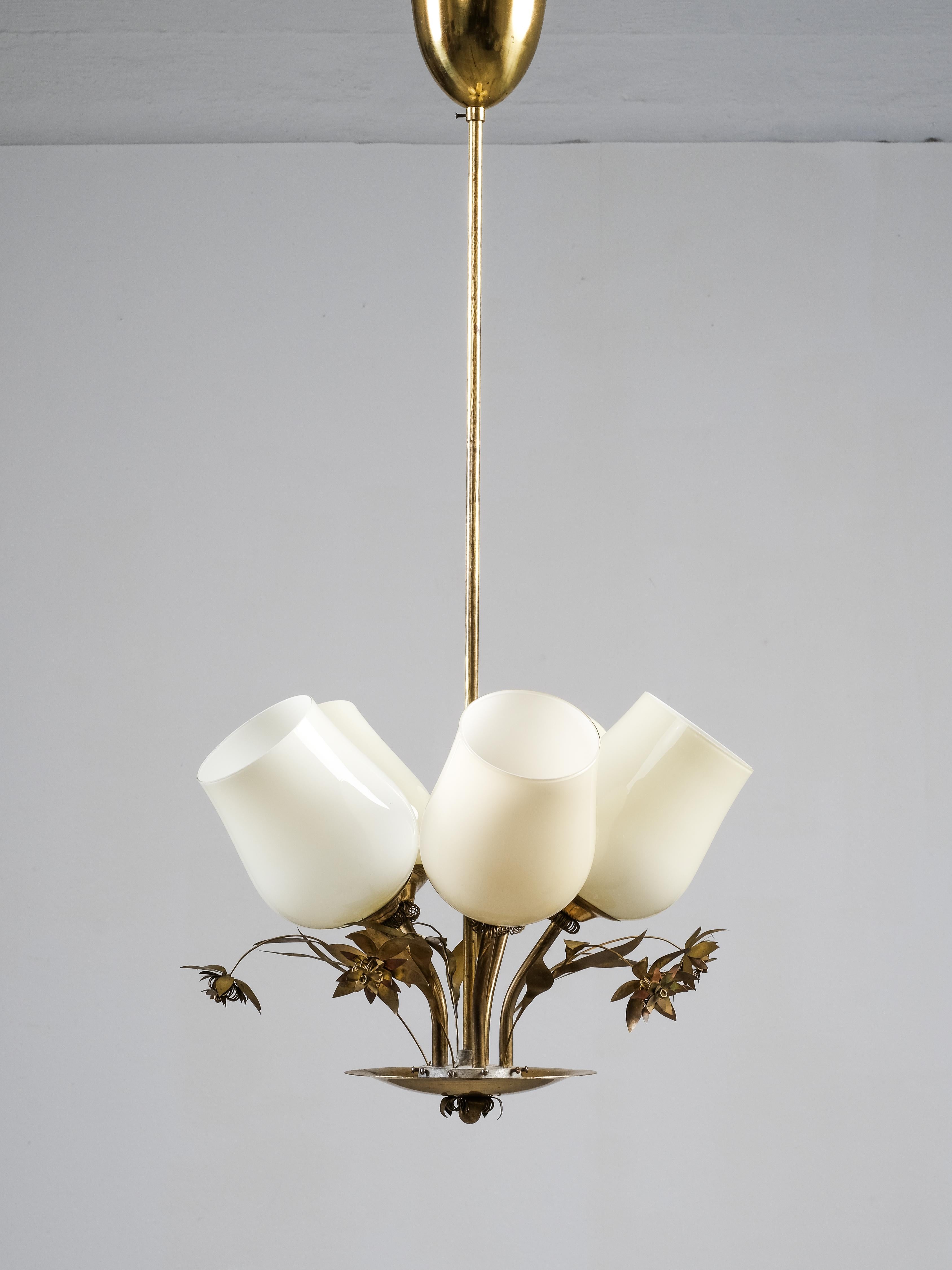 Una hermosa y delicada lámpara finlandesa de latón de mediados de siglo, de Stockmann. La lámpara tiene cinco portalámparas con pantallas de cristal opalino y bonitas decoraciones florales de latón entre cada una. Tiene sorprendentes similitudes con