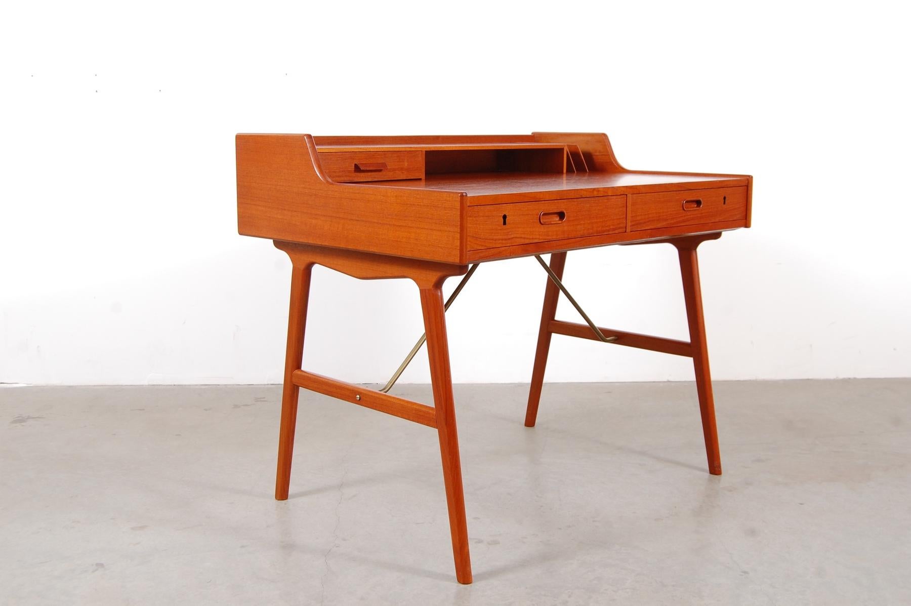 Wonderful Danish writing desk designed by Arne Wahl Iversen in 1961, model 56 for Vinde Møbelfabrik with splayed legs with solid brass stretchers, tabletop with drawer, storage shelf, and solid teak dividers for mail. Marked Danish design and