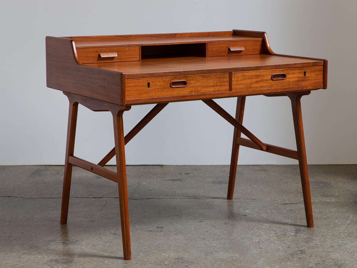 Handsome teak desk by Arne Wahl Iversen for Vinde Møbelfabrik. This compact yet functional desk is beautifully constructed, with added features for office organization. Spacious writing surface topped with a drawer and shelf. Deep dovetailed drawers