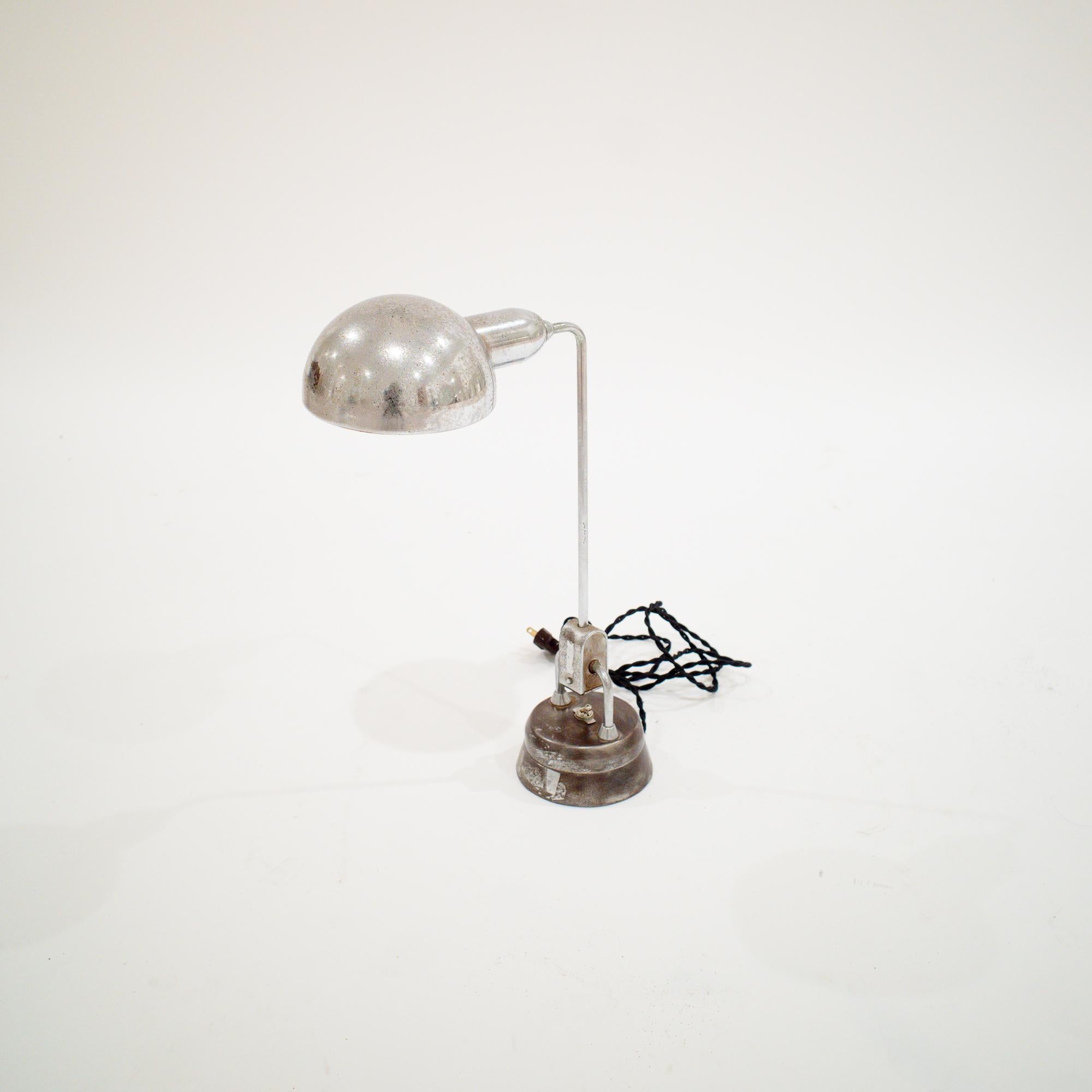 Fabrice en acier tubulaire chromé, la lampe Design/One 600 conçue par André Mounique et Yves Jujeau sous le nom de JUMO se caractérise par un bras articulé élancé, ancré à une base cylindrique lestée qui abrite l'interrupteur rotatif intégré. Le