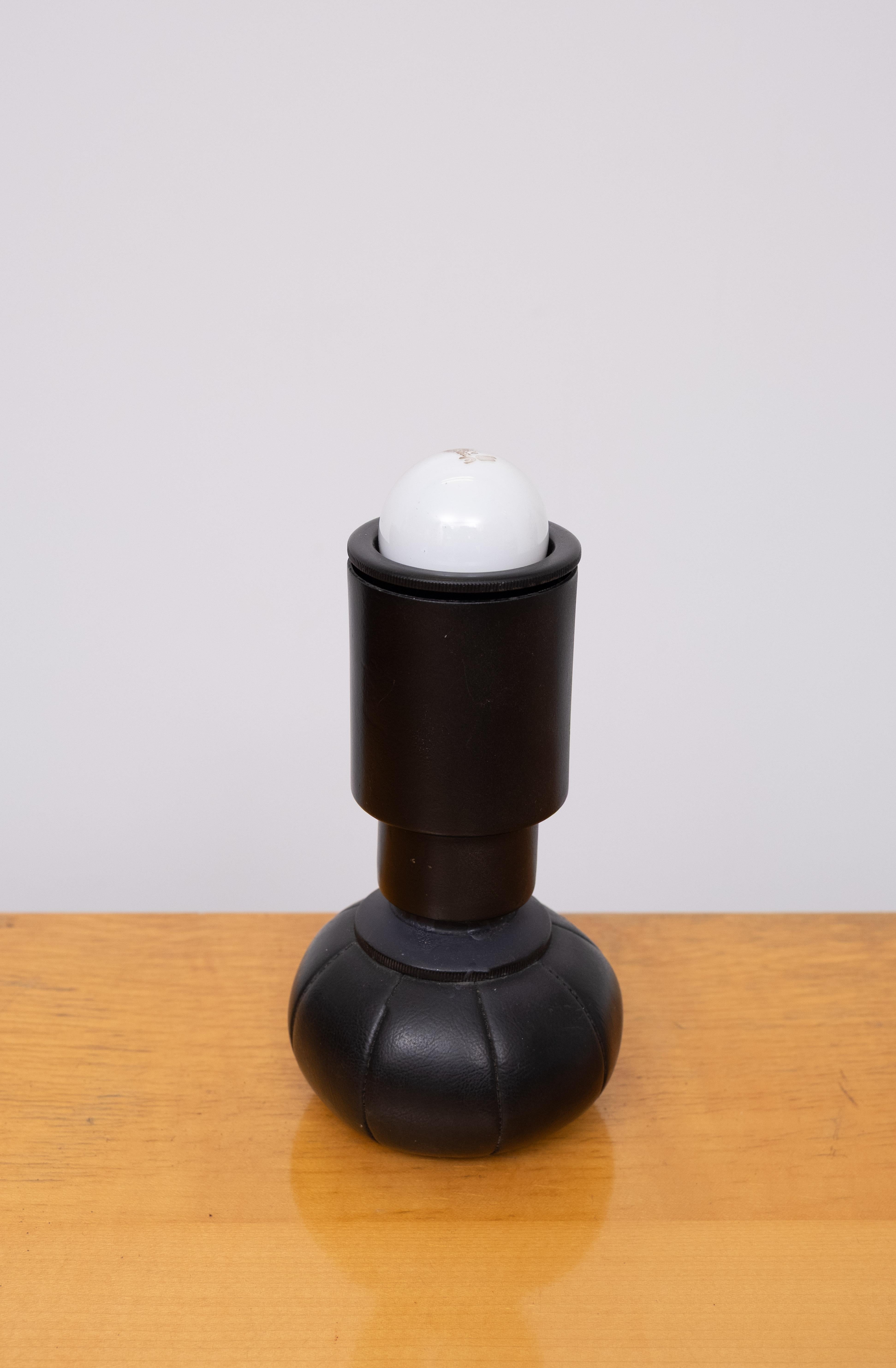 Lampe de table noire mod. 600/C  conçu par le maître Gino Sarfatti, fabriqué par sa propre société Arteluce. 

Conçue en 1966, produite de 1960 à 1969

Aluminium laqué. La base en cuir est remplie de petites billes de plomb qui permettent à la lampe