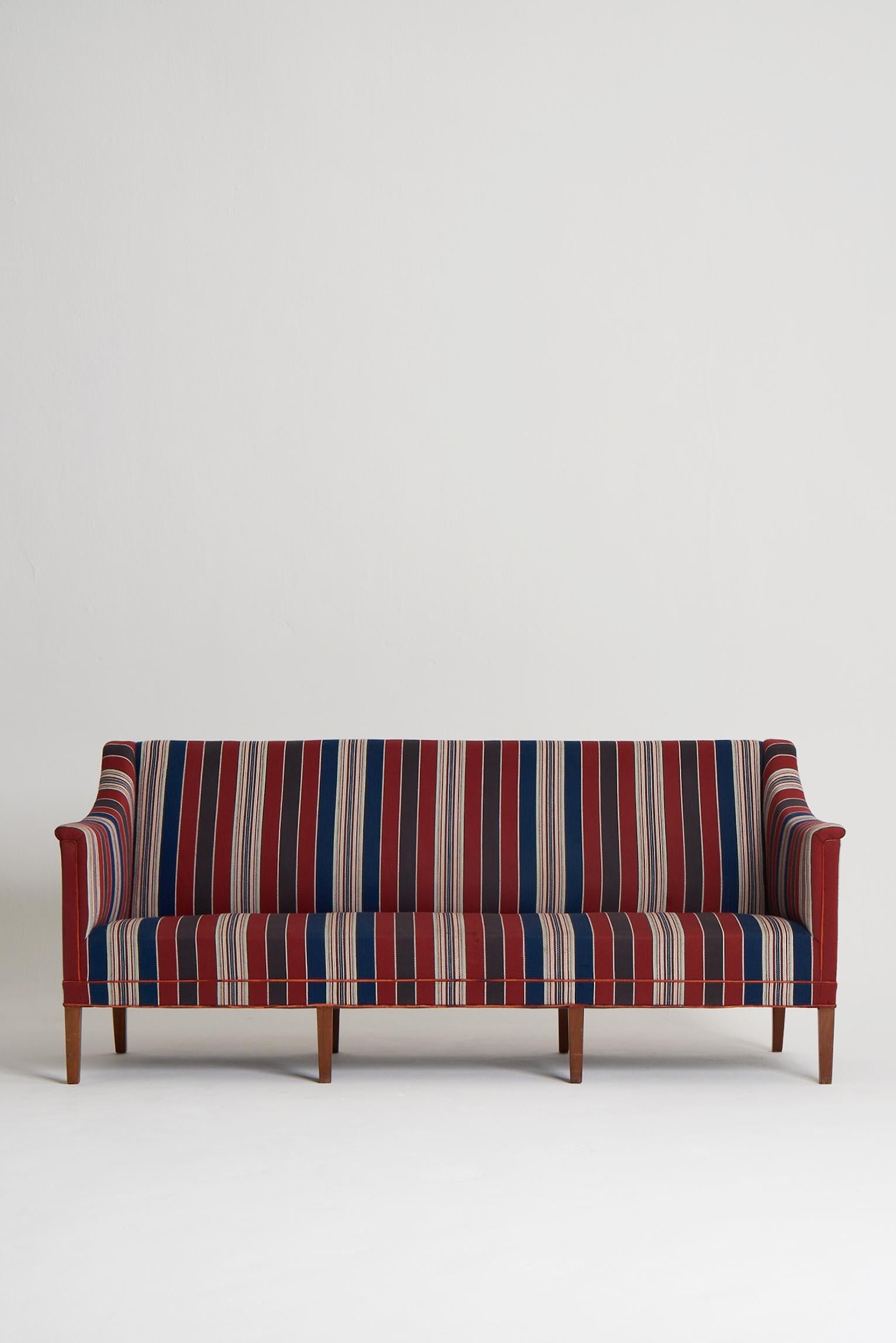 A vintage model 6092 three to four seat sofa designed by Kaare Klint (1888-1954) for Rud Rasmussen.
The sofa stands on eight tapered solid mahogany legs and is upholstered in its original 'Greek Fabric' which was also designed by Klint in