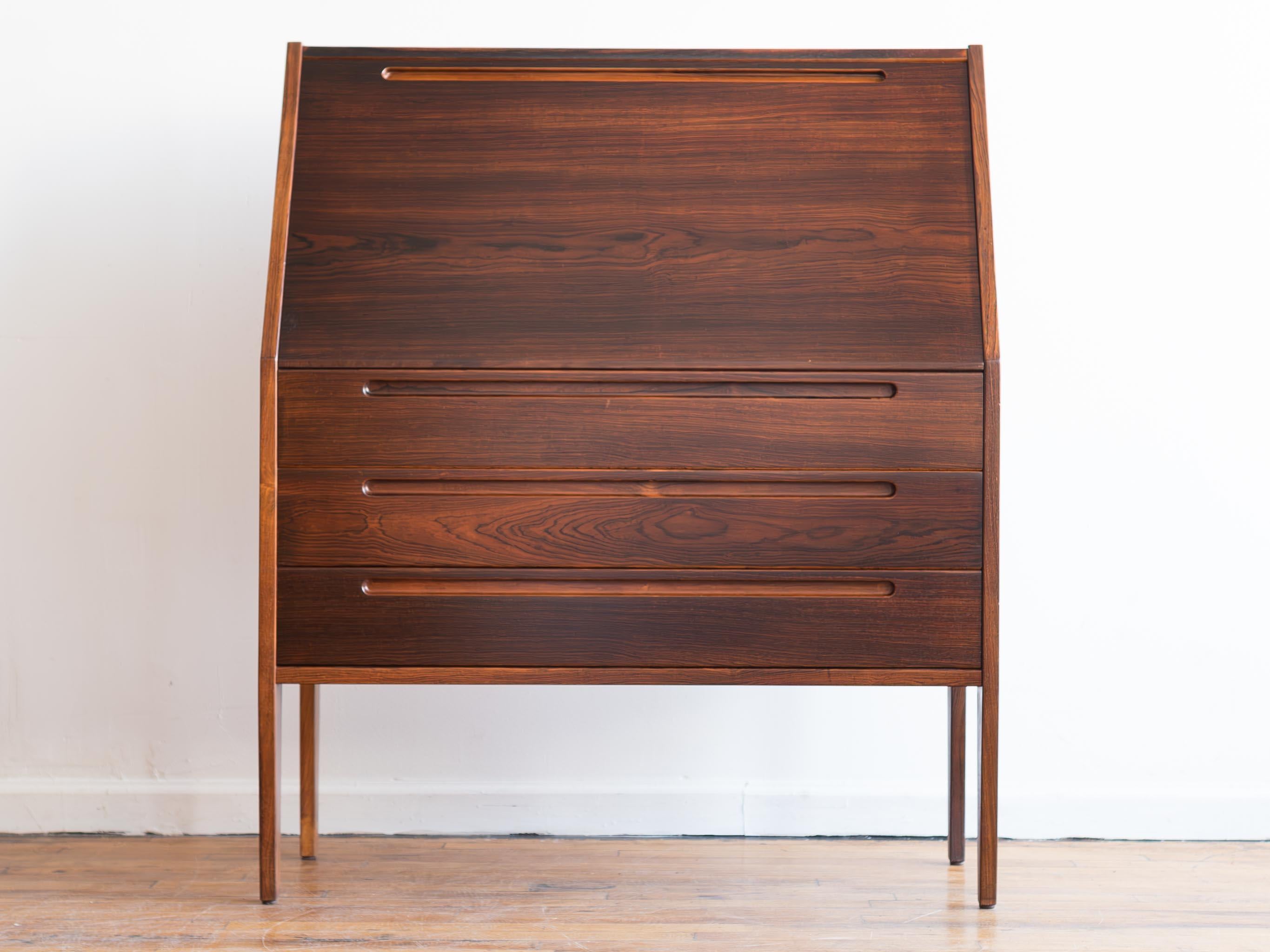 35.25” x 17” x 43”H; desk height 27”

Rosewood secretary desk by Kai Kristiansen for HNJ Møbler/Tørring Møbelfabrik (Denmark), circa 1960s. (Sometimes attributed to Nils Jonsson.)

•thee large lower drawers
•three upper drawers in dovetailed solid