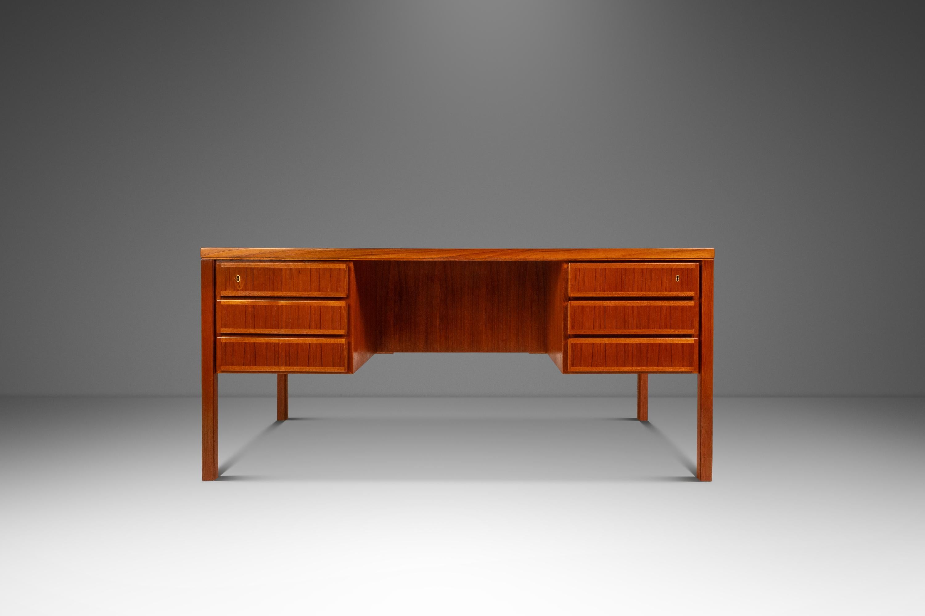 Questa iconica scrivania danese di metà secolo Model 77 in teak, disegnata da Gunni Omann e prodotta da Oman Junn, esemplifica l'eleganza del design scandinavo di metà secolo. Realizzata in ricco teak con una calda finitura naturale, la scrivania