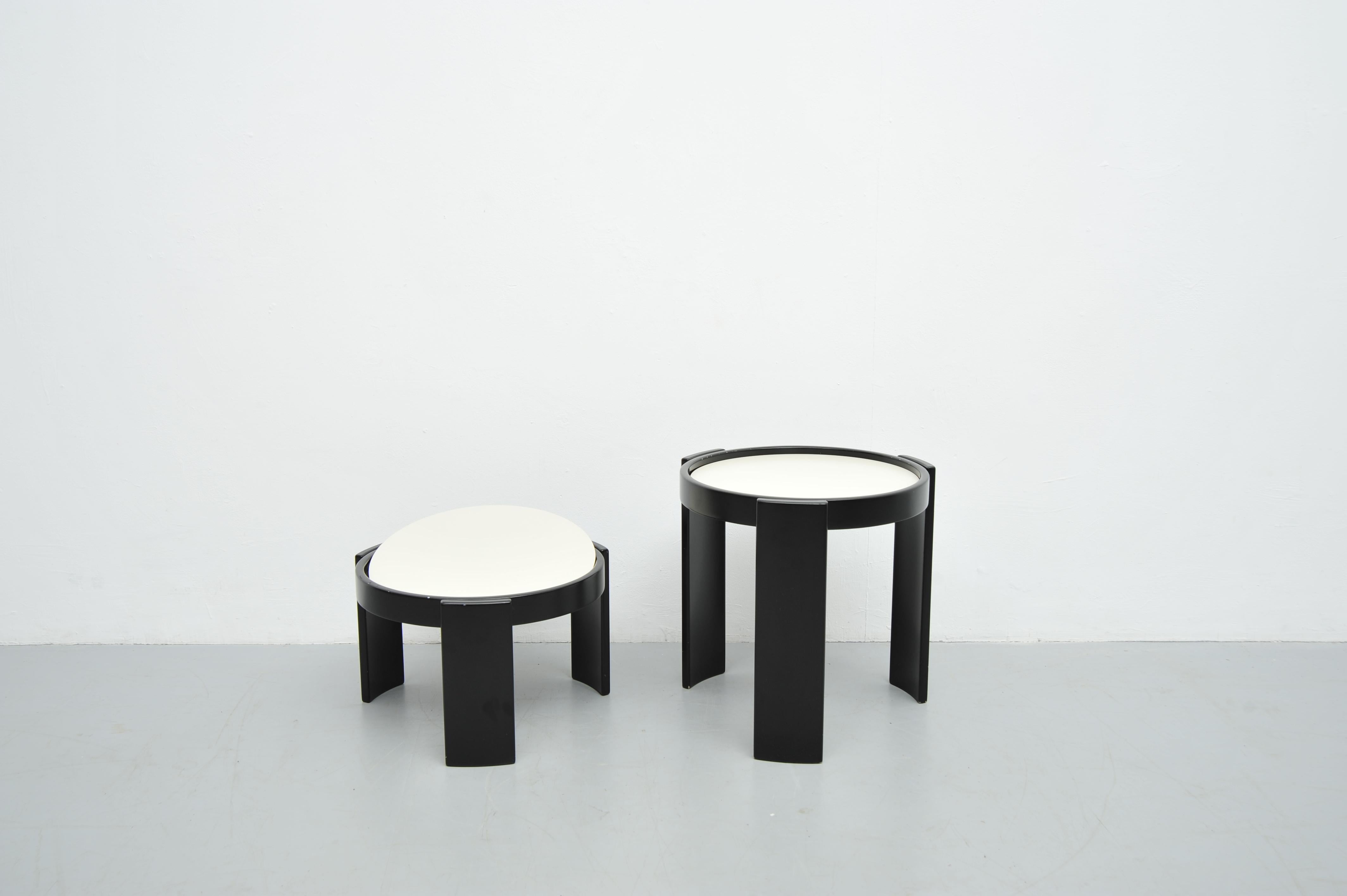 Questo set di due tavolini impilabili, disegnato da Gianfranco Frattini per Cassina, esemplifica l'eleganza e la versatilità del design italiano di metà secolo. Realizzati negli anni '60, i tavoli presentano una struttura in legno laccato nero