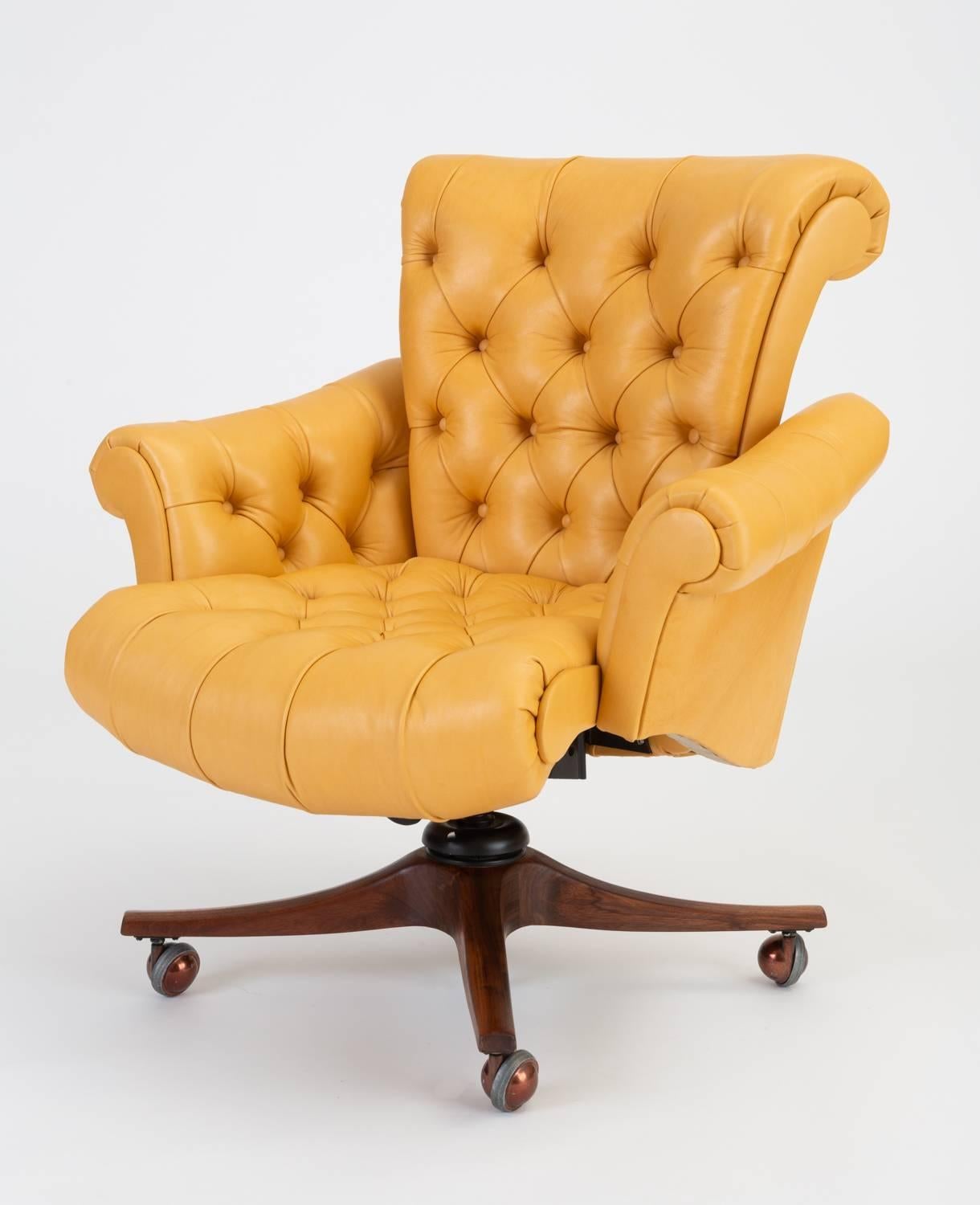 Extravagant modernism from Edward Wormley for Dunbar, the 932 executive desk chair has high back and splayed scroll armrests on either side of a button tufted chair seat. The adjustable chair sits on a base of solid walnut wood with brass casters.