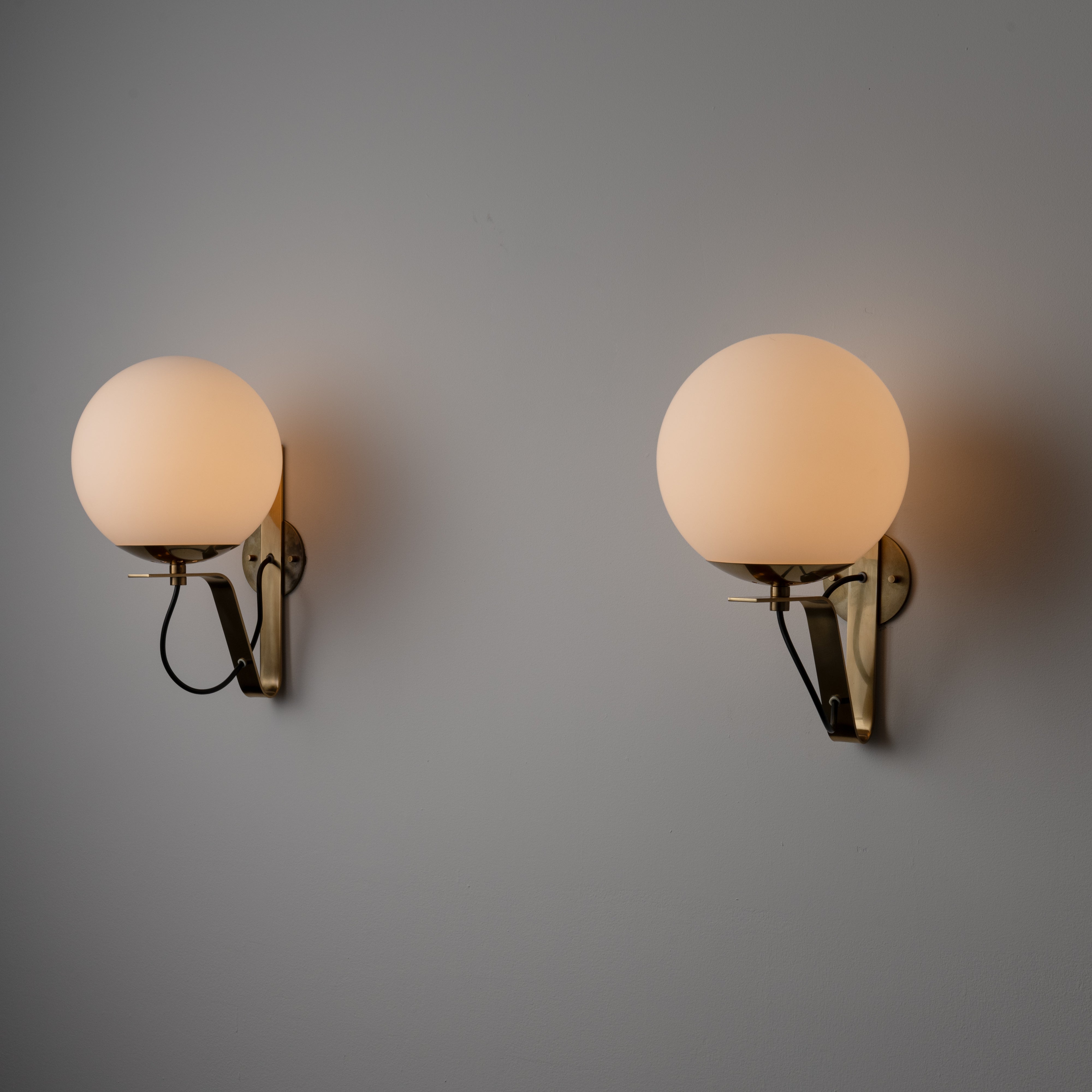 Model b464 sconces by Sergio Asti for Candle. Designed and manufactured in Italy circa 1960. Sconces are mounted by polished brass L-shaped bracket which seamlessly hold a frosted white globe over bulb socket. Custom US backplate added. We recommend