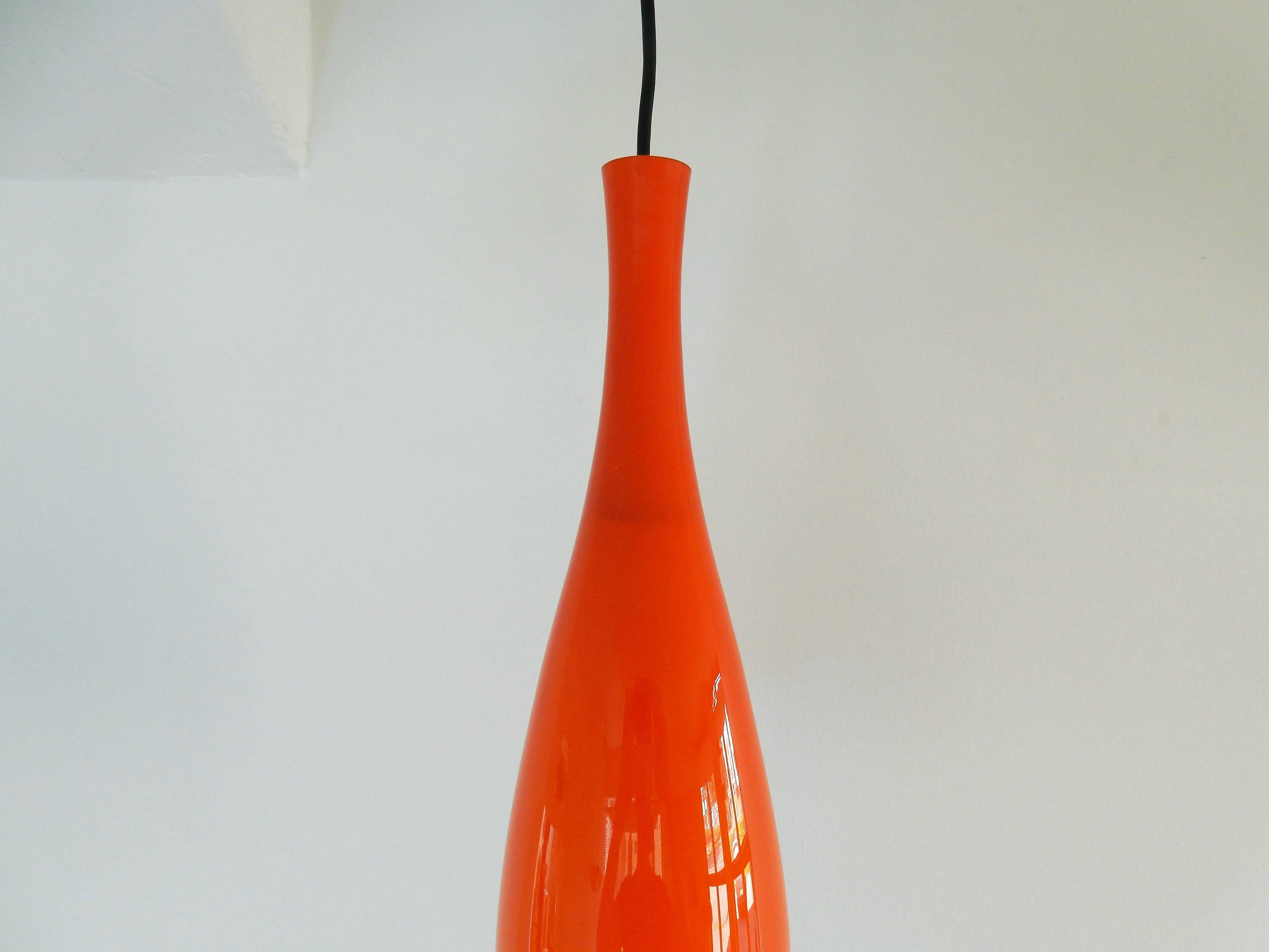 This Mid-Century Modern pendant lamp gives a beautiful warm light with its orange opaline glass. It is in a very good condition with minor signs of age and use. This glass pendant was produced by Holmegaard for Fog & Mørup.