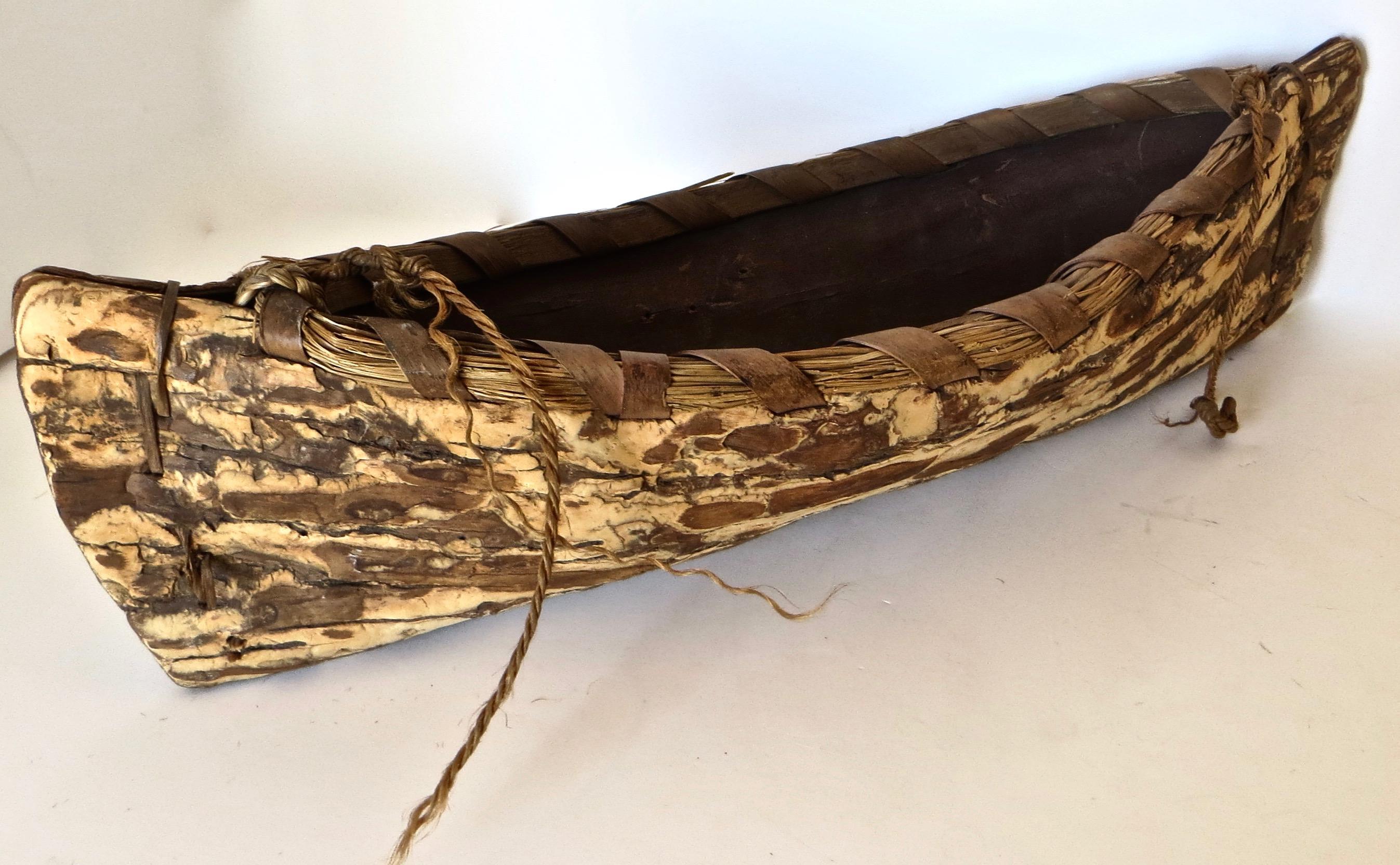 Pre-war Folk Art dugout canoe is made of spruce bark, and carved by the Iroquois Indian tribe, the indigenous people of the Eastern Woodlands to the south of Lake Ontario in the Great Lakes region. The exterior is natural tan and brown in color with