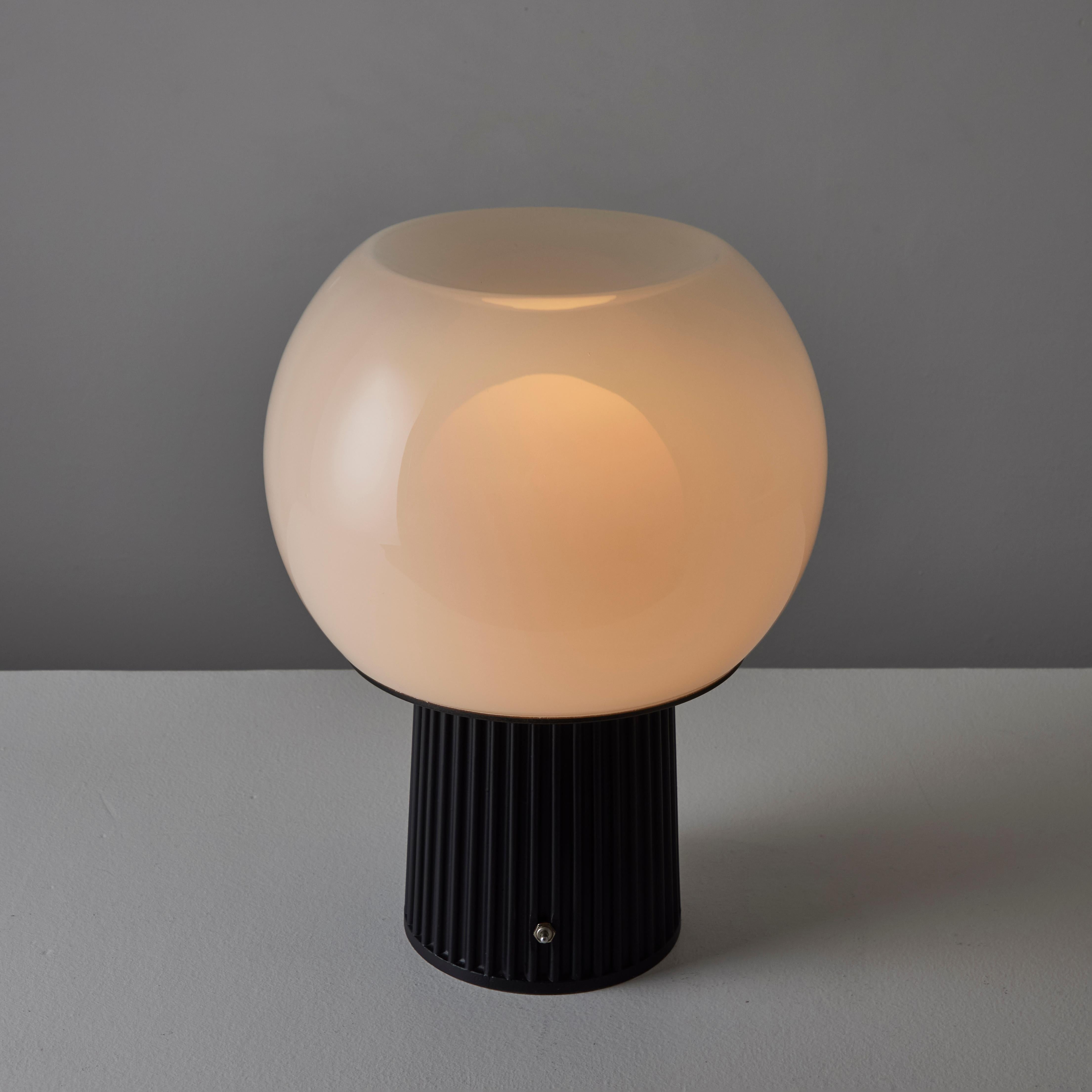 Model D573 Table Lamp by Candle. Designed and manufactured in Italy, circa the 1960s. A black enameled ribbed table base holds a toggle switch at front center. The diffusion comes from an outer concave hand-blown milk glass globe, as well as an