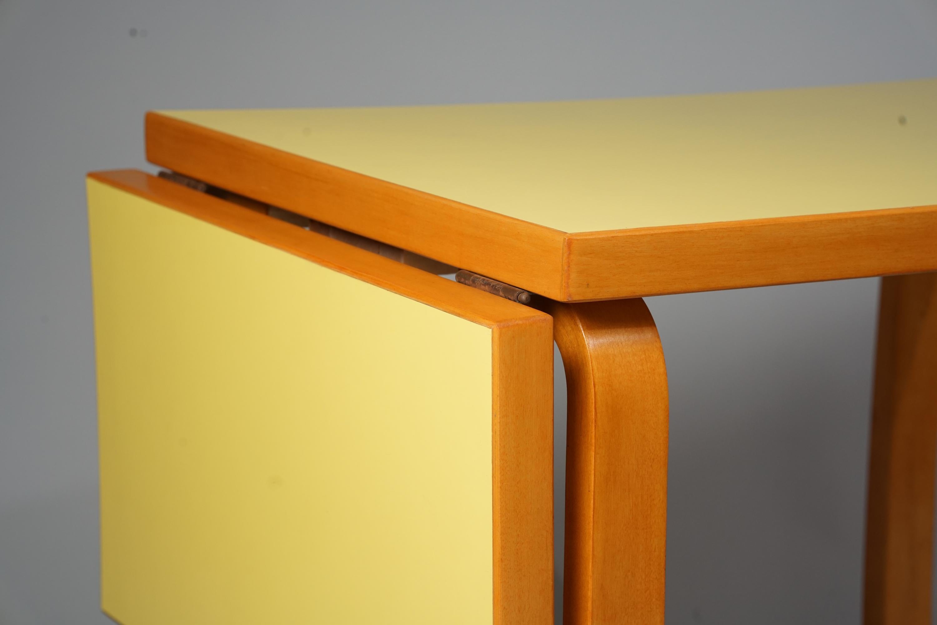 Tavolo da pranzo allungabile Model DL 82, design di Alvar Aalto, prodotto da Oy Huonekalu- ja Rakennustyötehdas Ab, anni Cinquanta. Splendida struttura in betulla rifinita color miele con raro piano in laminato giallo. Il tavolo ha una parte