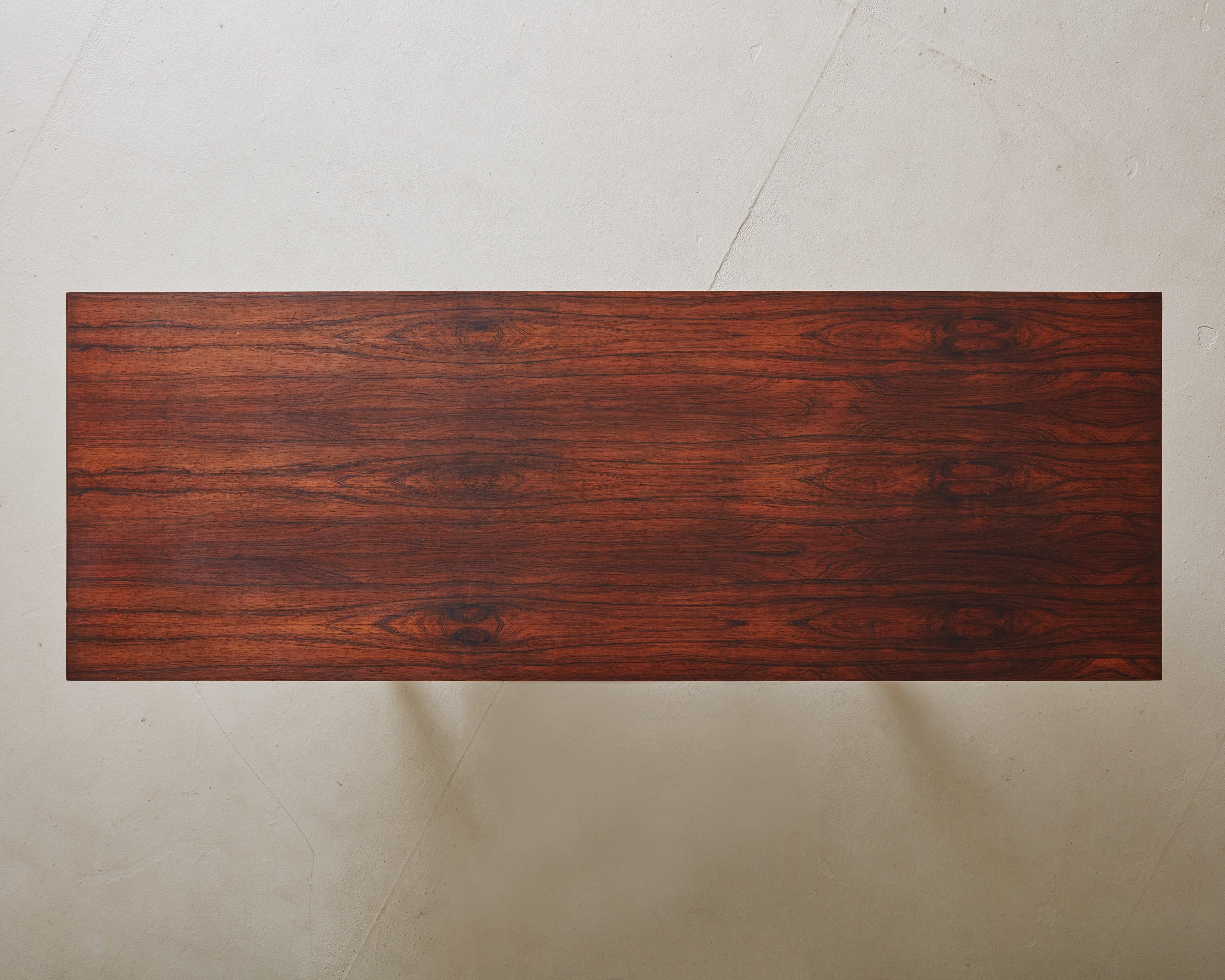 A 1960s Danish Modern ‘Model ML 115’ rosewood coffee table attributed to Illum Wikkelsø for Mikael Laursen. The minimalist silhouette features a rectangular tabletop supported by distinctive V-shaped legs, which are connected by a central stretcher