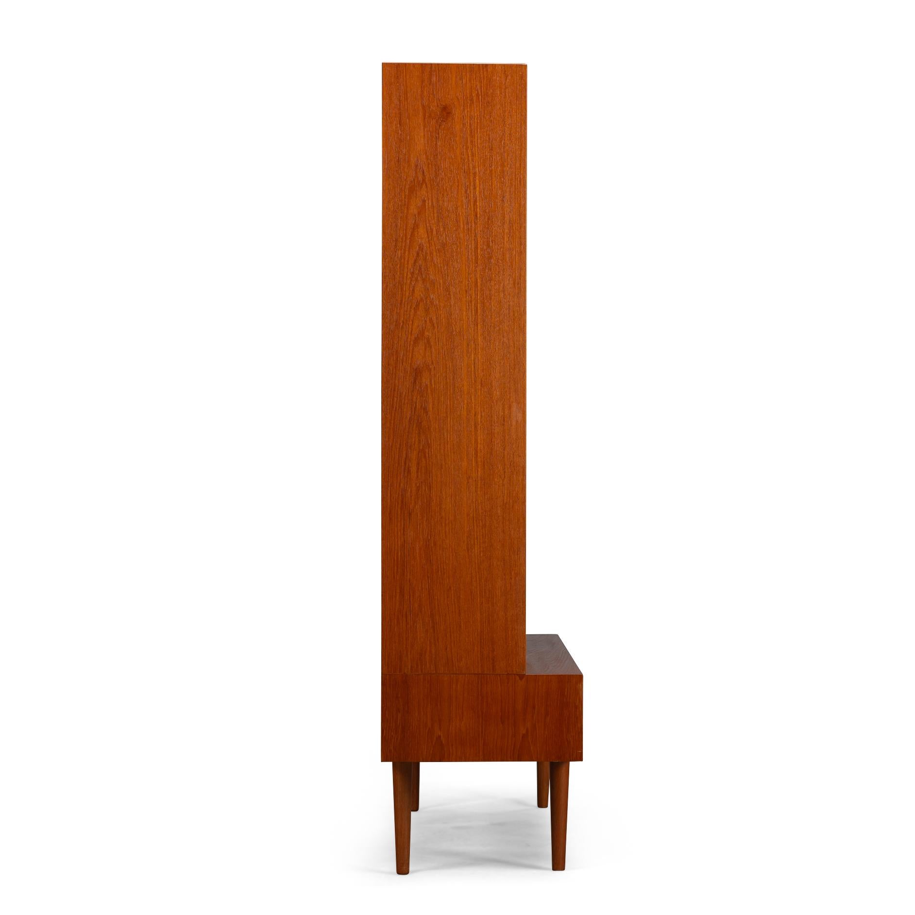 Danish Design
Introducing the Hundevad No. 26 bookcase with a seperate small sideboard underneath, a stunning example of midcentury modern Danish design. This unique piece combines a small low sideboard with a separate bookcase on top, creating a
