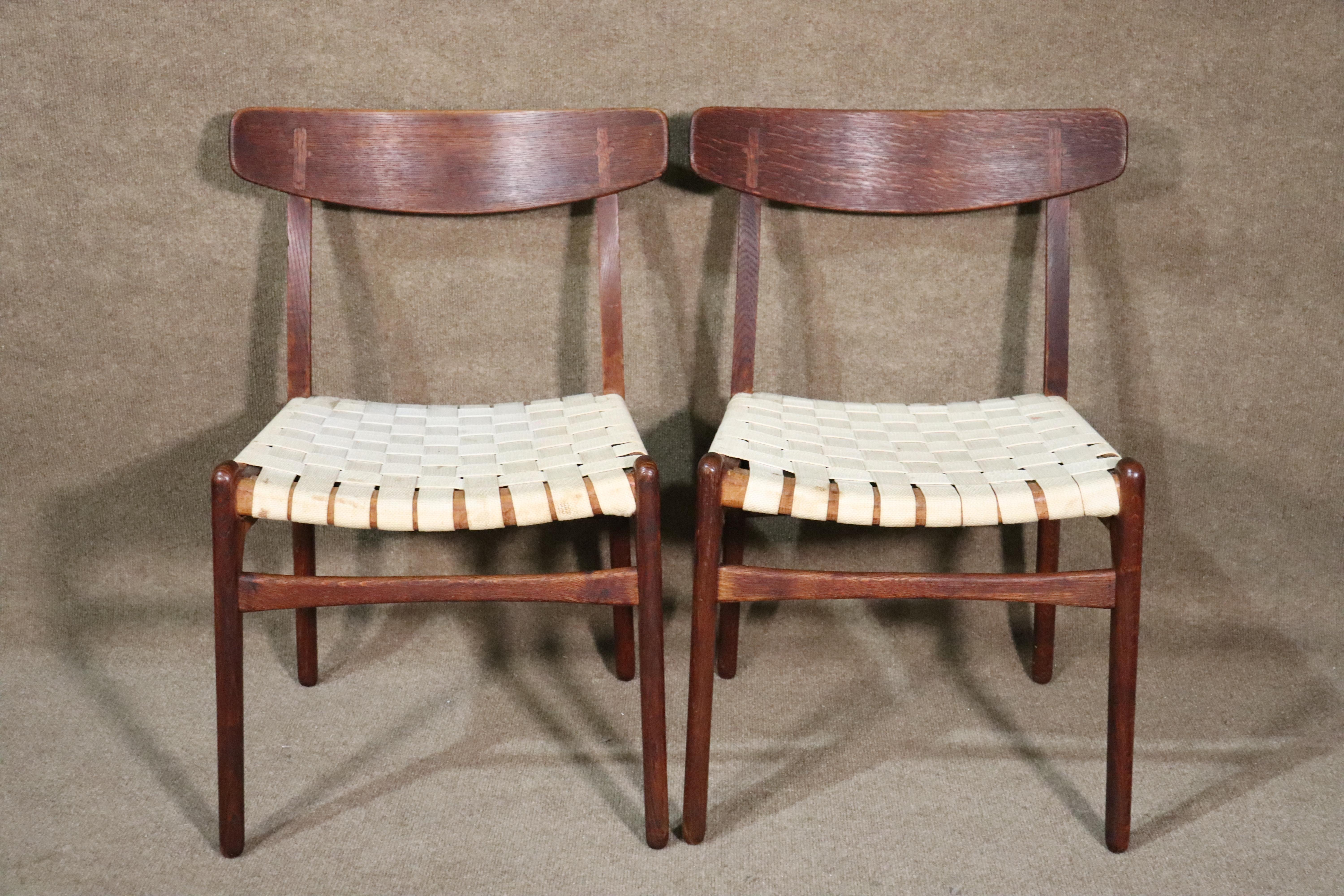 Set of four dining chairs designed by Hans Wegner. Iconic mid-century modern design with webbed seating and inlay cross on seat backs.
Please confirm location.