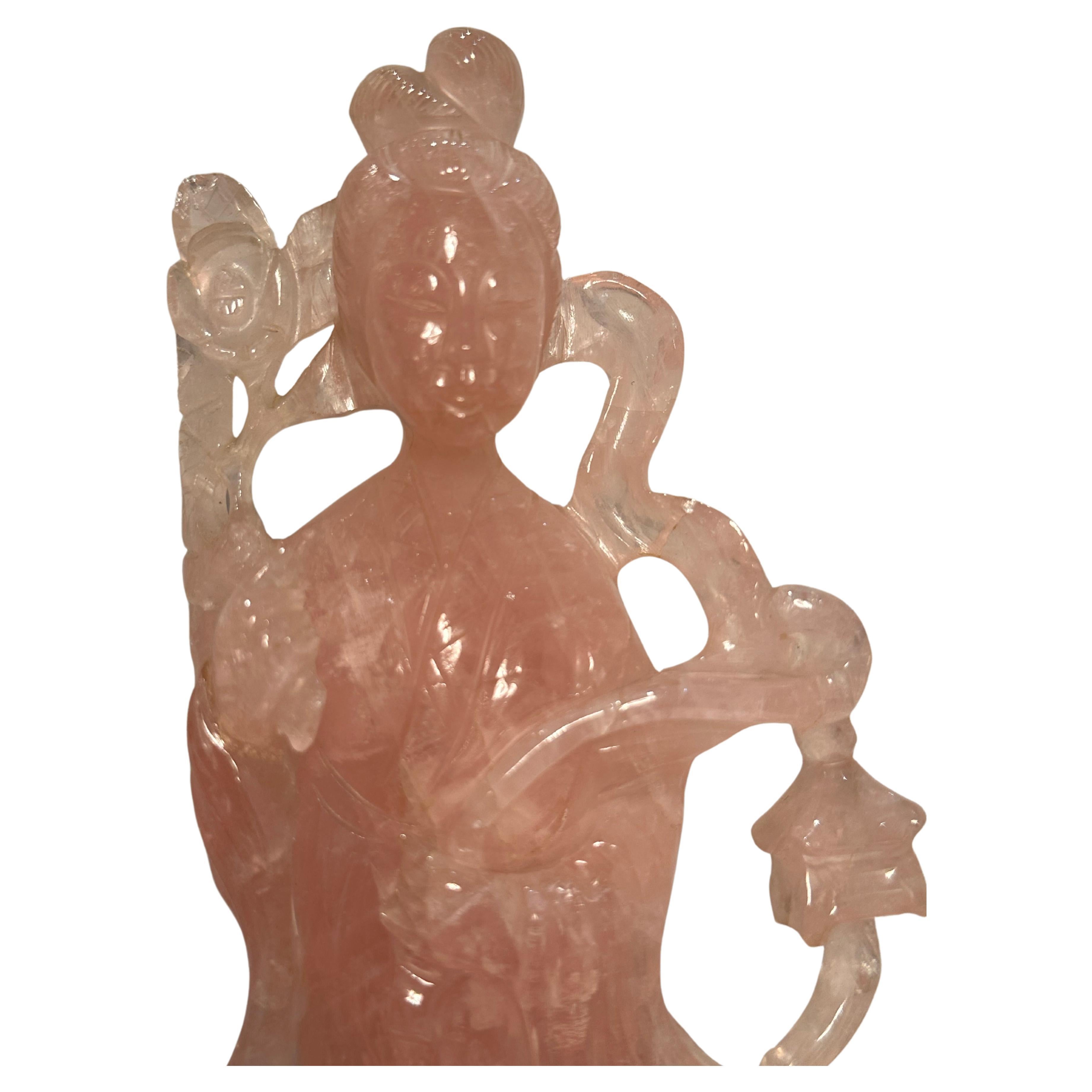 Exquisit handgefertigte und handgeschnitzte rosa Rosenquarz-Figur der Göttin Quan Yin.  Sie ist mit einer Girlande aus Lotusblüten in der Hand abgebildet und steht auf einem handgefertigten und handgeschnitzten Ständer aus Rosenholz.

Quan Yin, auch
