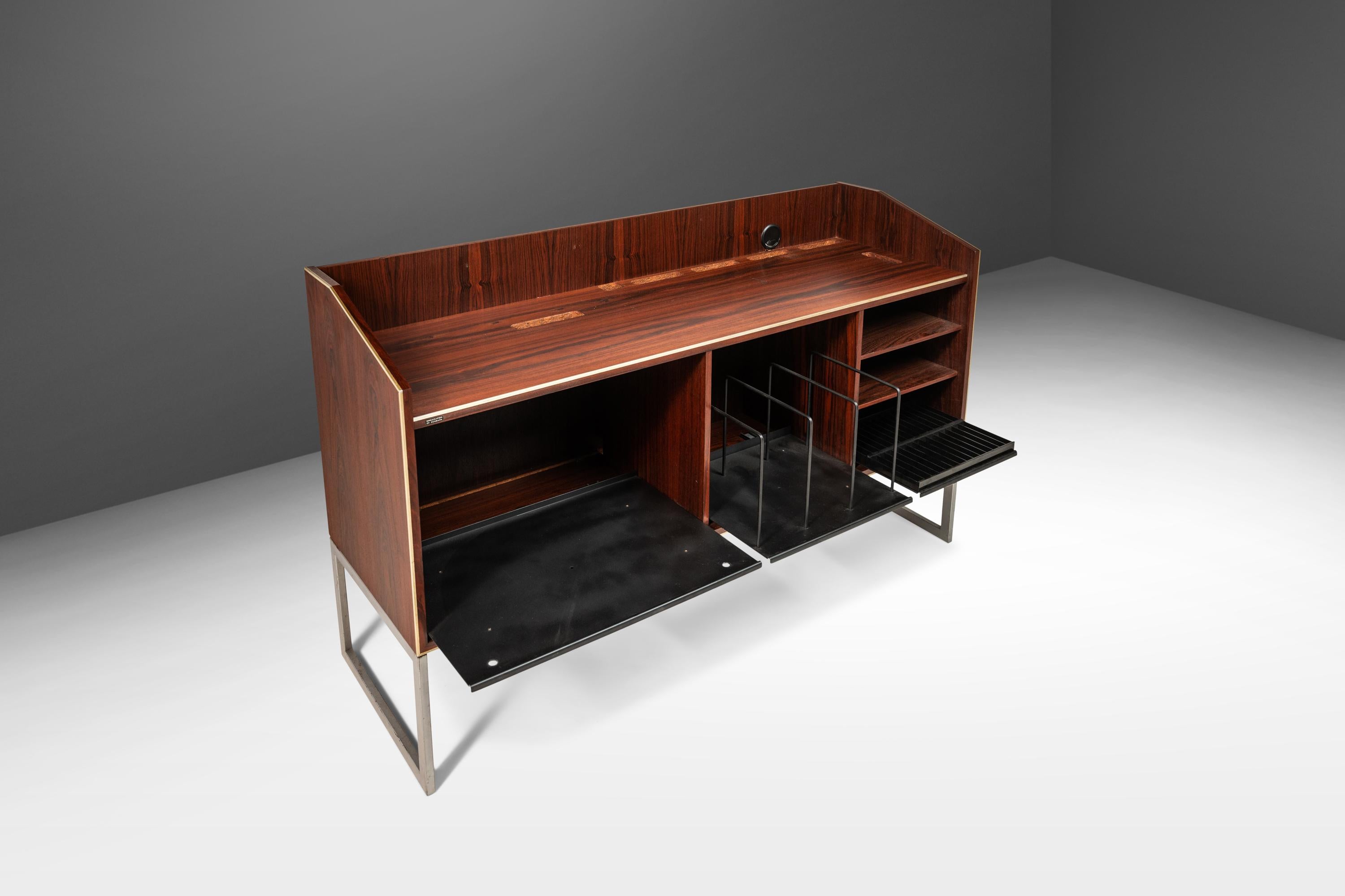 As stylish as it is functional this ultra-rare stereo console is a true retro gem. Constructed from a mix of steel and veneered Brazilian Rosewood with exceptional variegated woodgrains this console was built specifically for music lovers and
