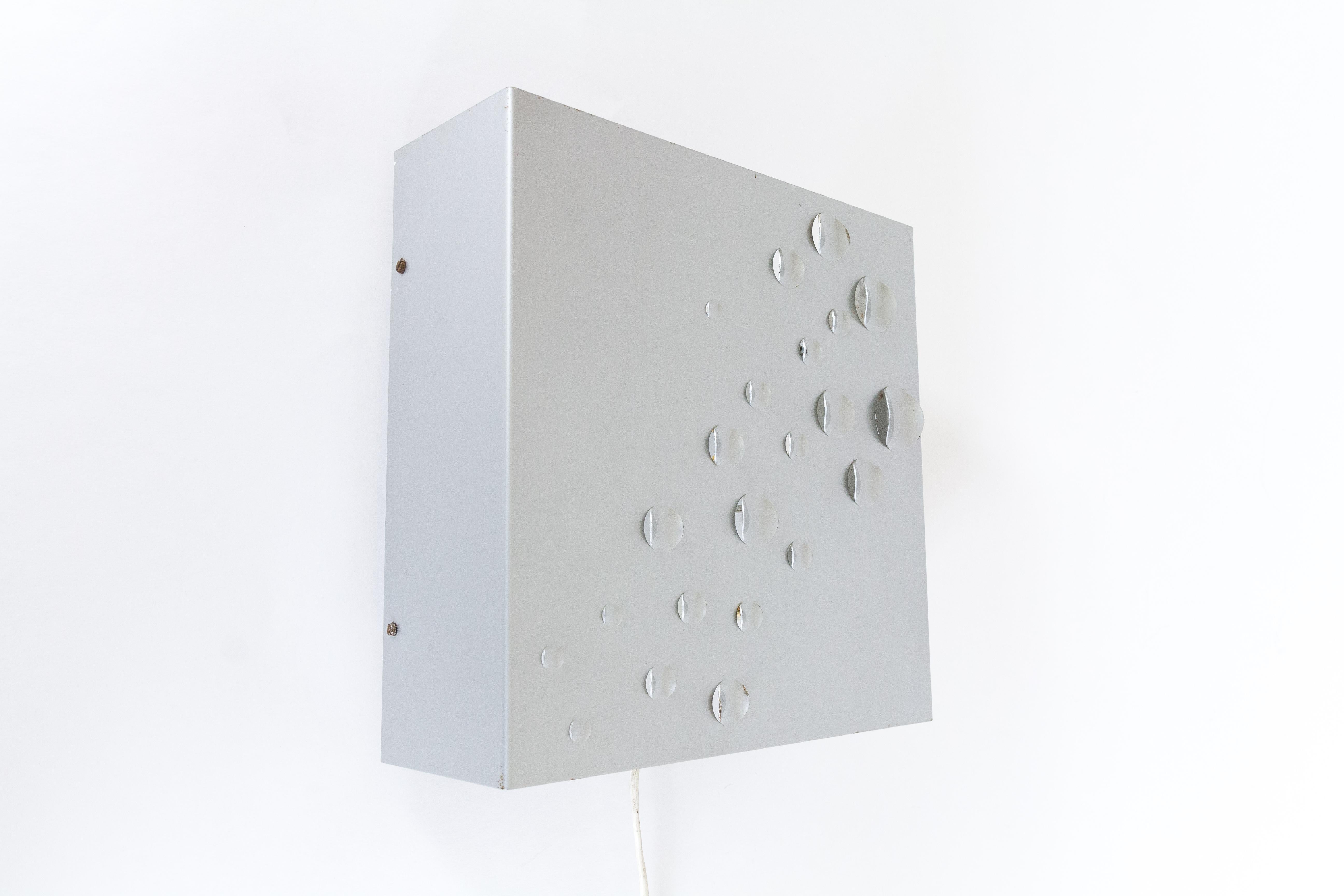 This wall lamp is called Sterrenregen (or in English: Meteor shower) and is designed by architect and designer Evert Jelle Jelles for RAAK Amsterdam, in The Netherlands in 1965. The lamp is made from enameled steel with pierced